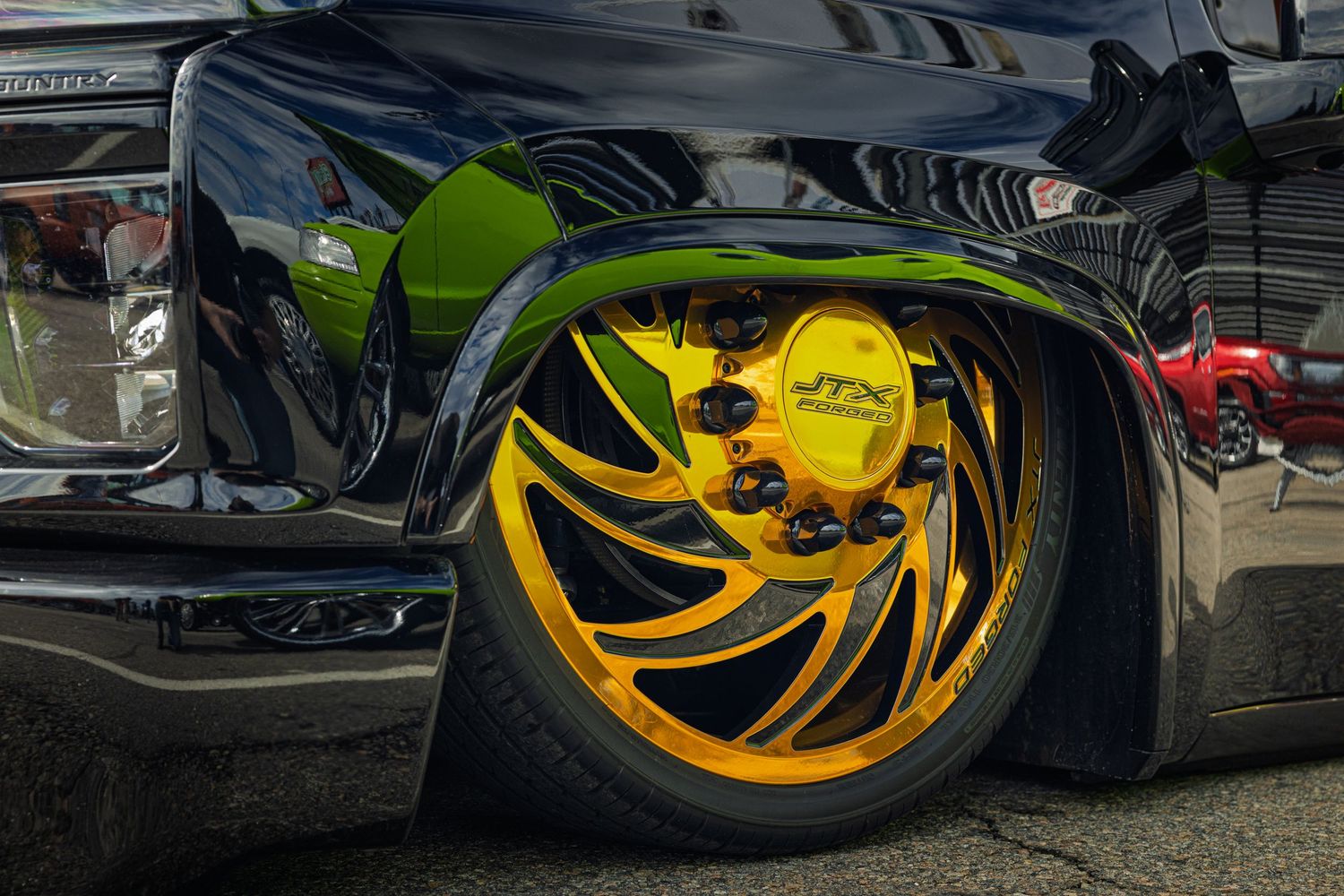 Close-up shots of custom yellow and gold chrome wheels on modified vehicles at a car show.