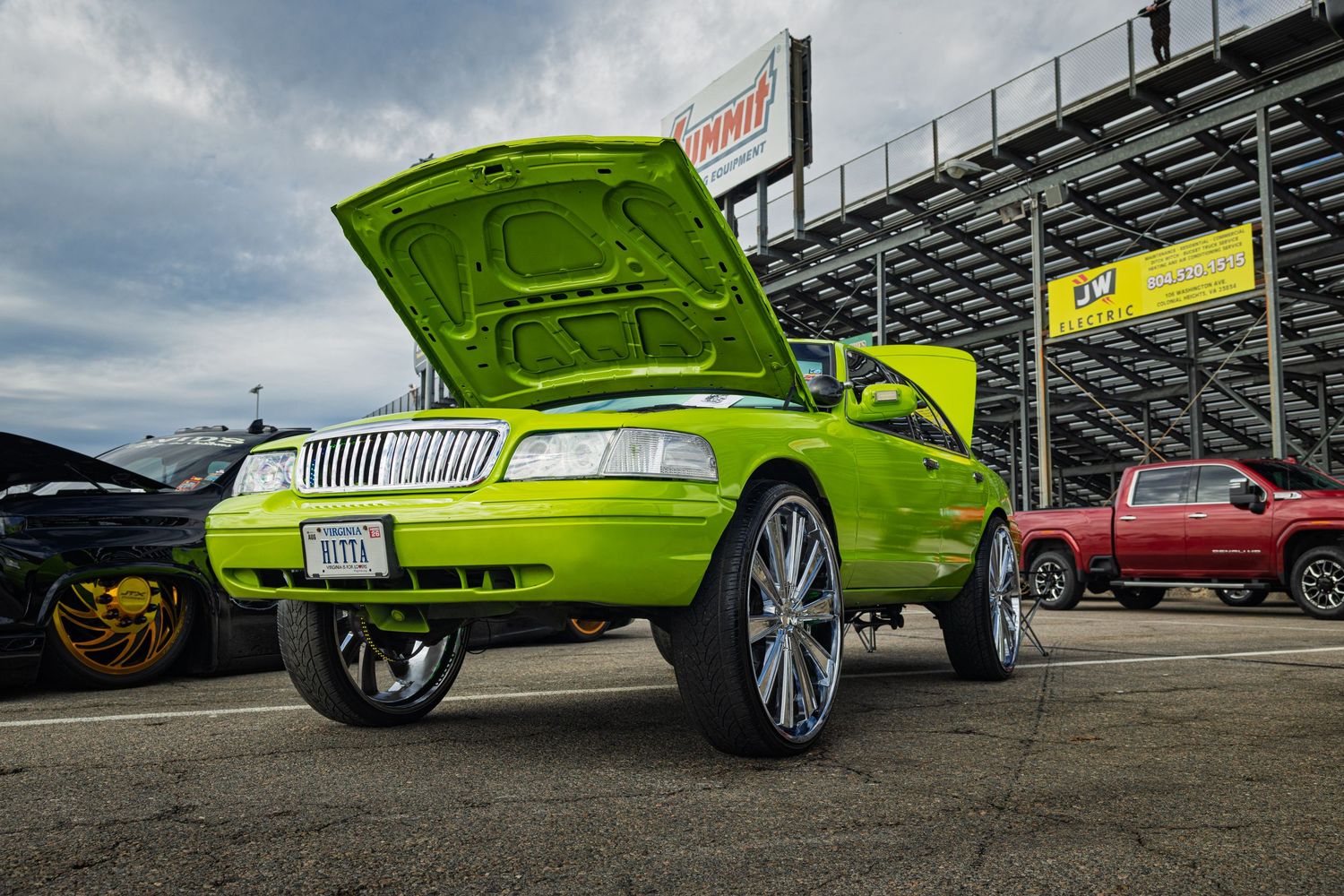 Lime green custom car with lowered suspension and chrome wheels parked at a car show.
