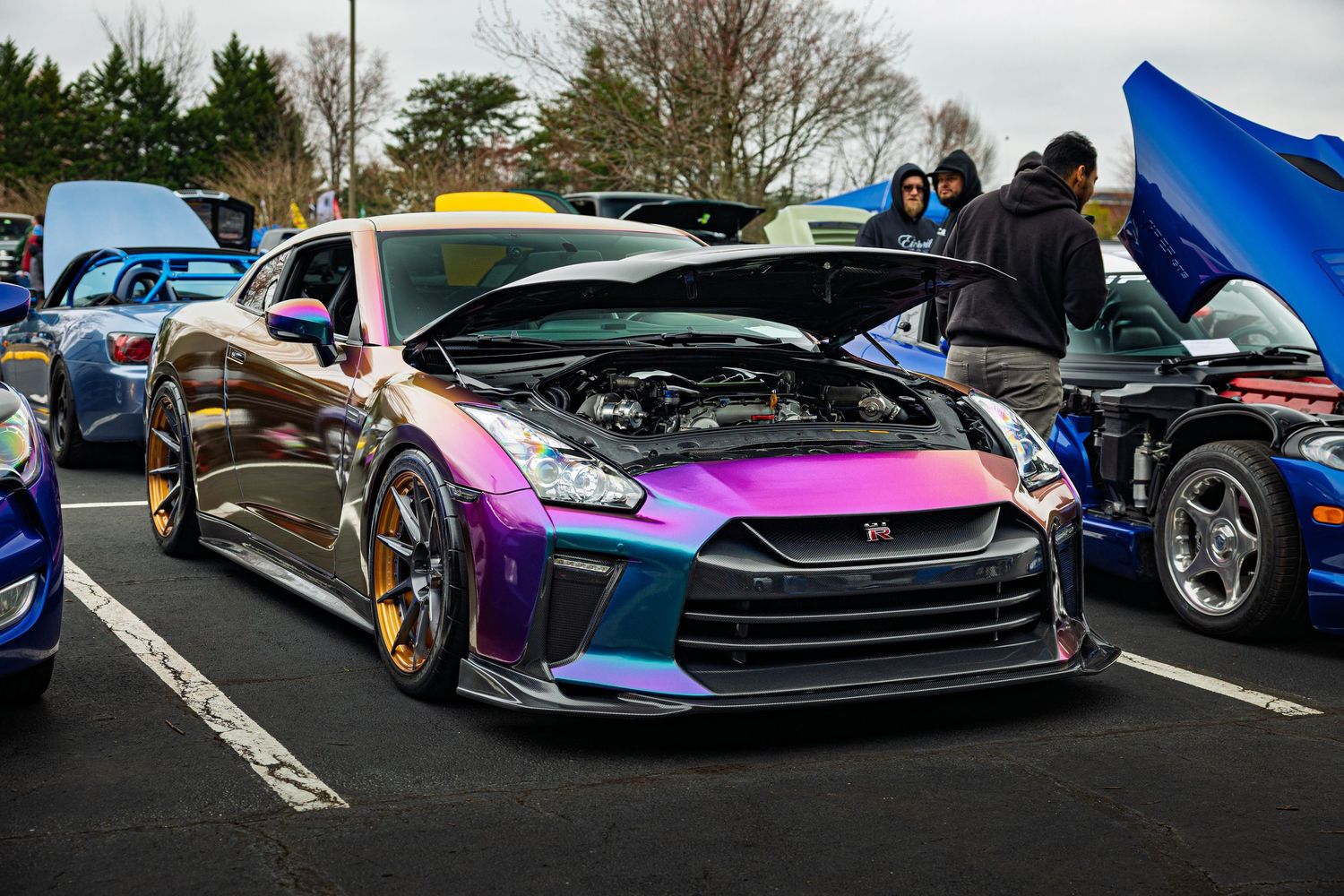Custom Nissan GTR with iridescent color-shifting paint finishes displayed at a car show event.