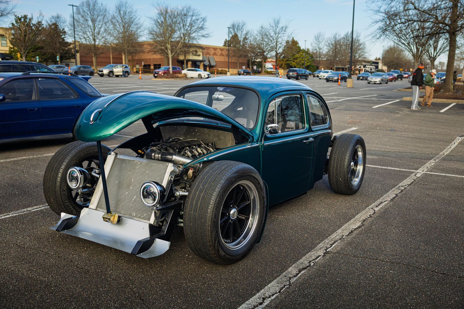 A series of vintage custom hot rods and classic cars parked in a row at a car show parking lot.