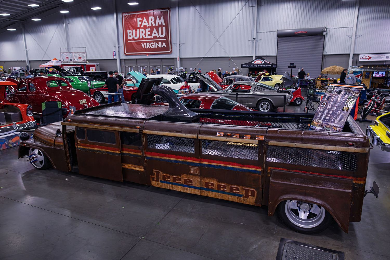 Custom brown lowrider truck with wood paneling displayed at indoor car show among other classic vehicles.