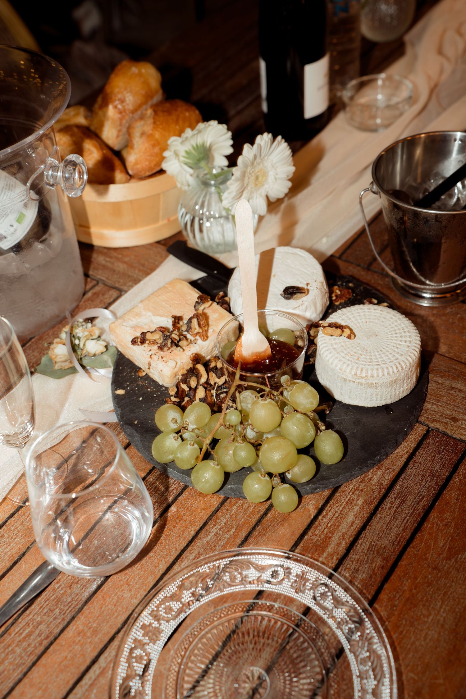Rustic cheese platter with grapes, bread, and wine on a wooden table.