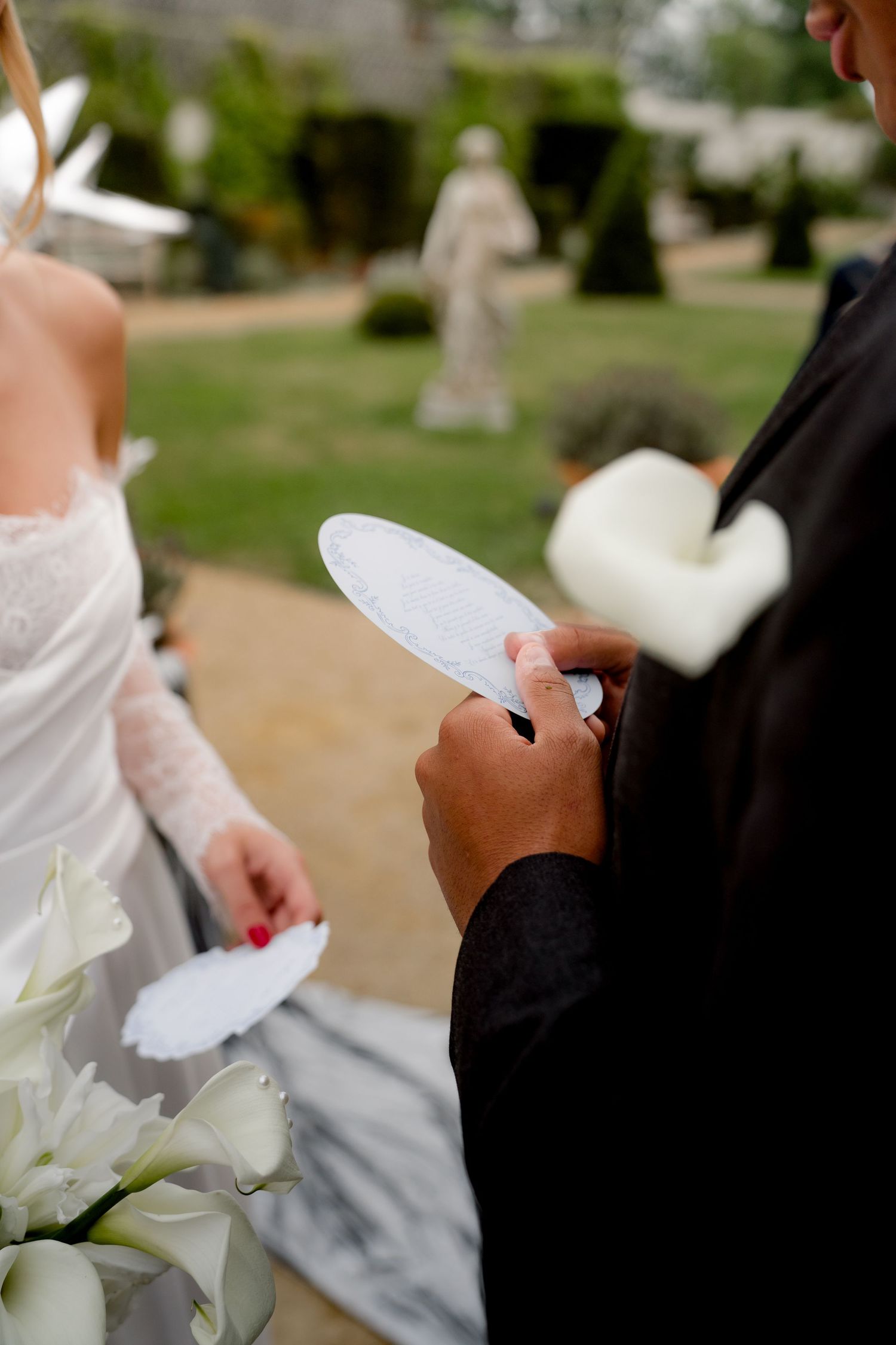 Close-up of groom reading handwritten vows from paper during outdoor wedding ceremony.