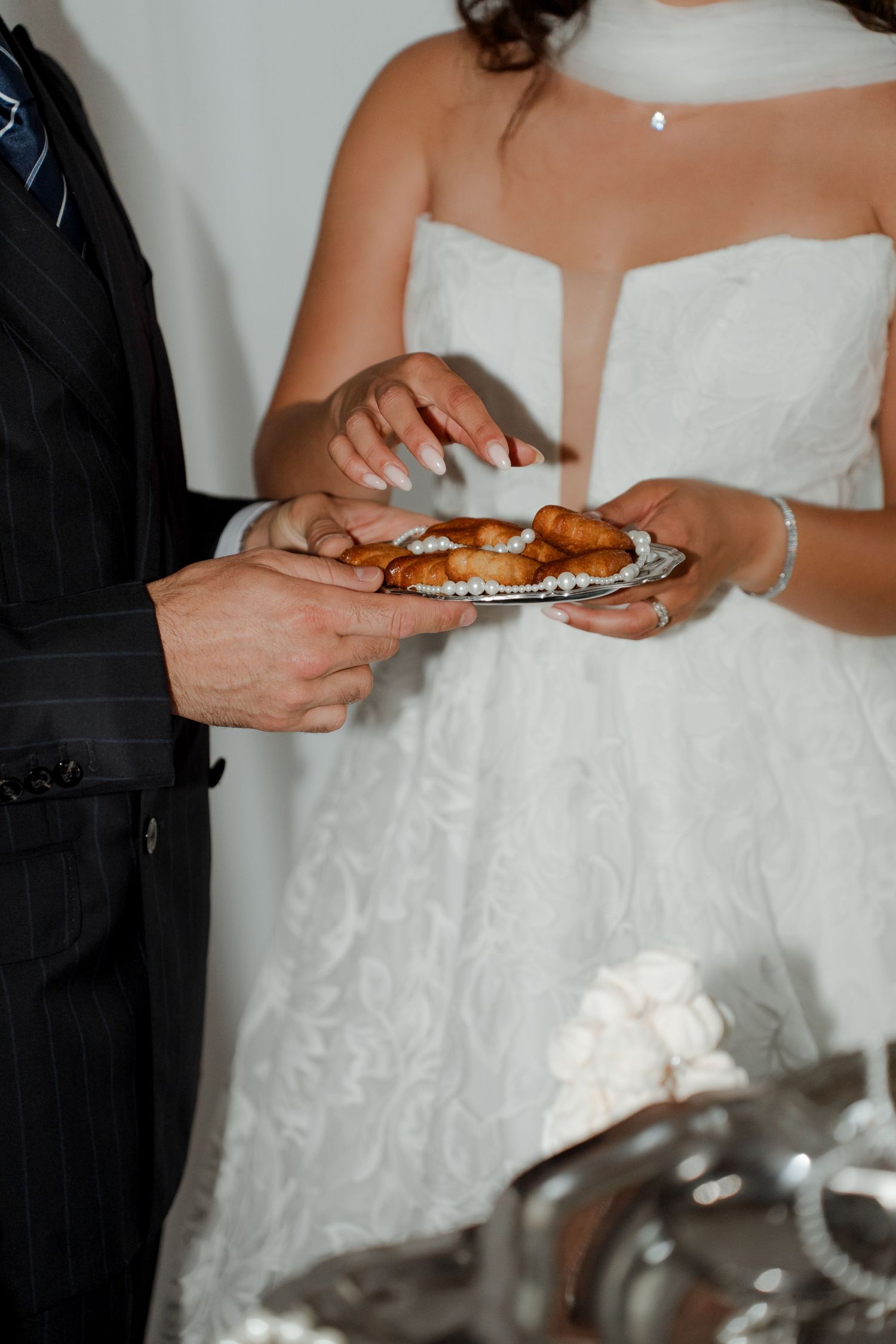 Bride and groom holding a silver tray with pastries during their wedding reception ceremony.