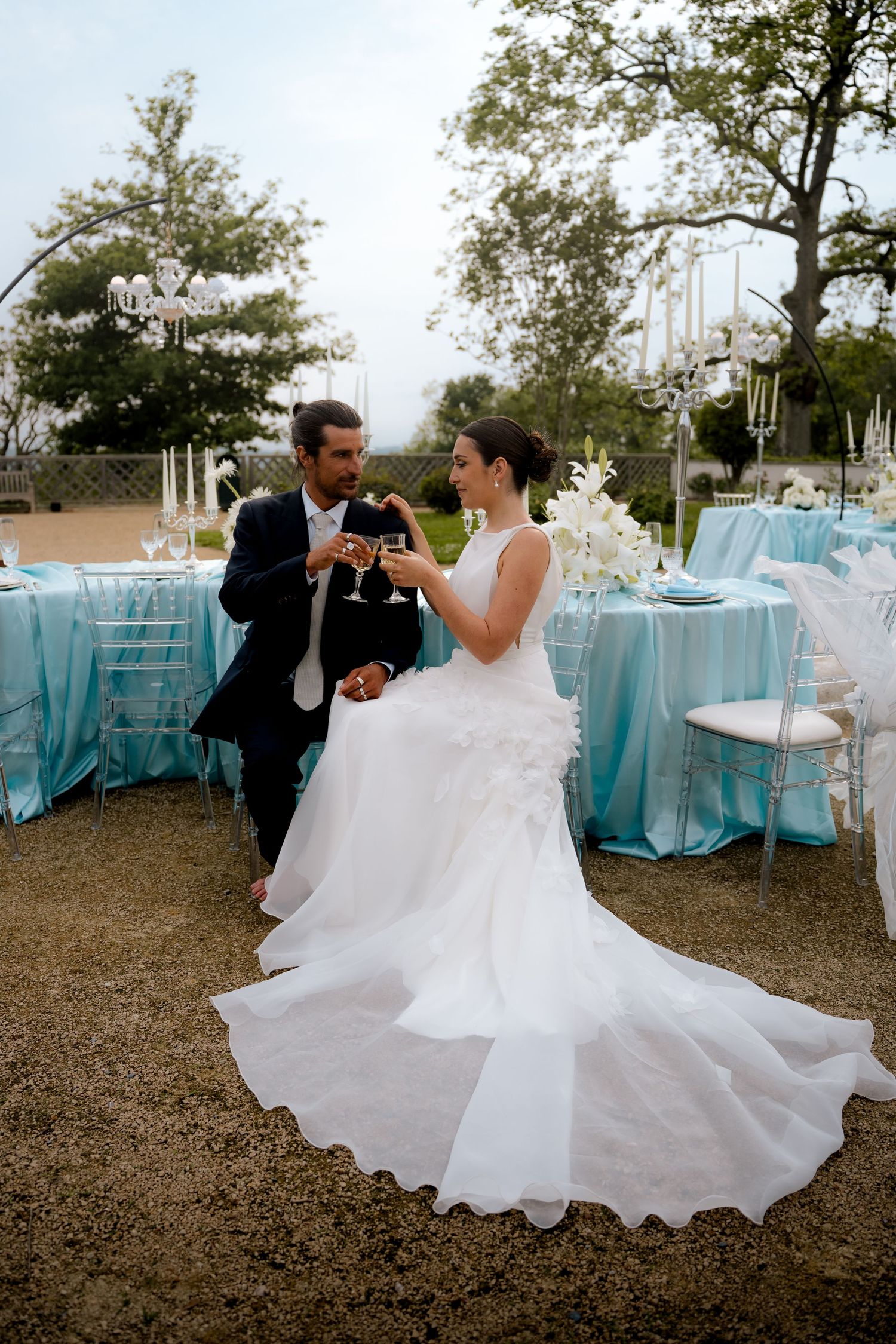 Bride and groom toasting champagne at elegant outdoor wedding reception with tiffany blue tablecloths.