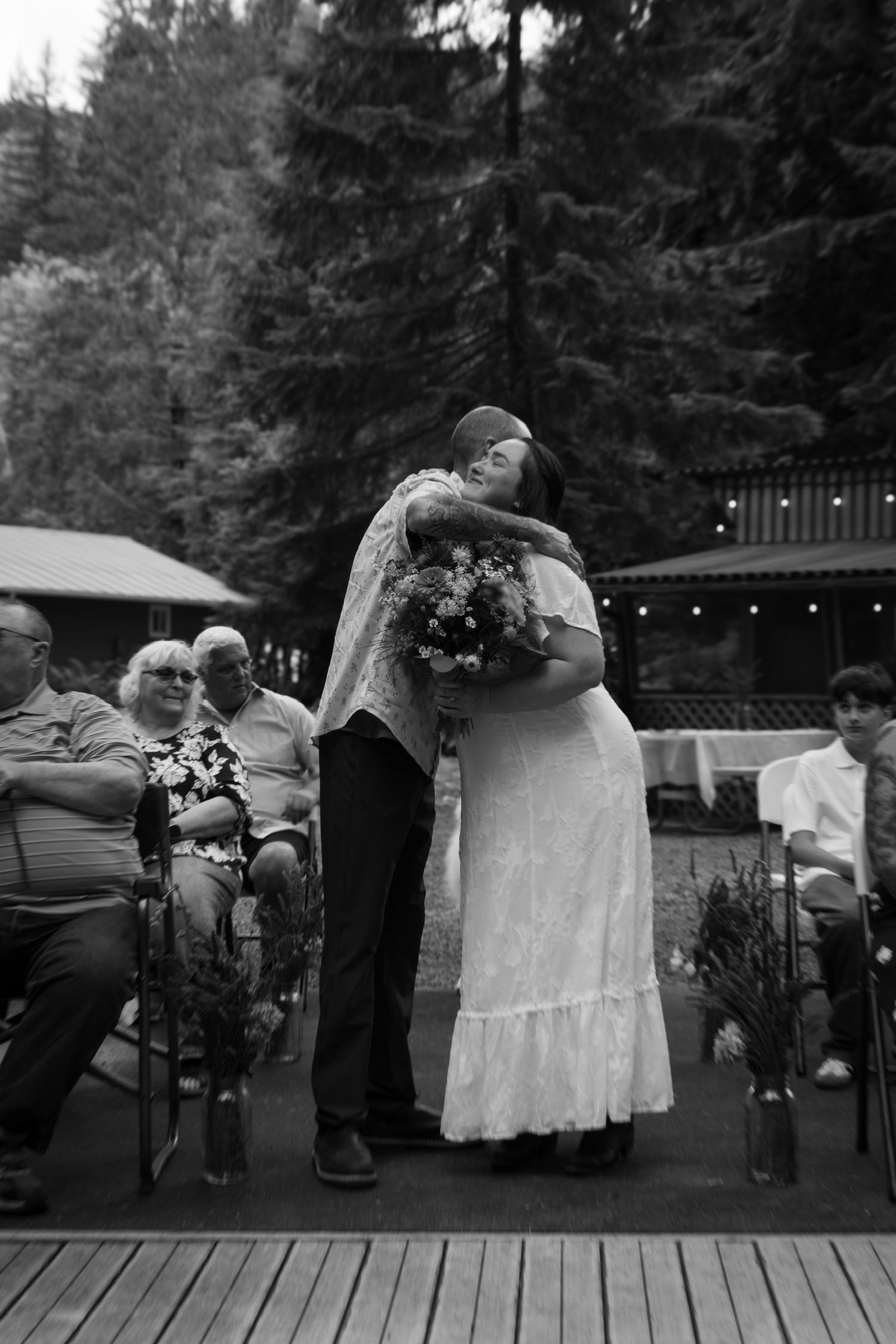 A tender embrace between newlyweds during an outdoor forest wedding ceremony.