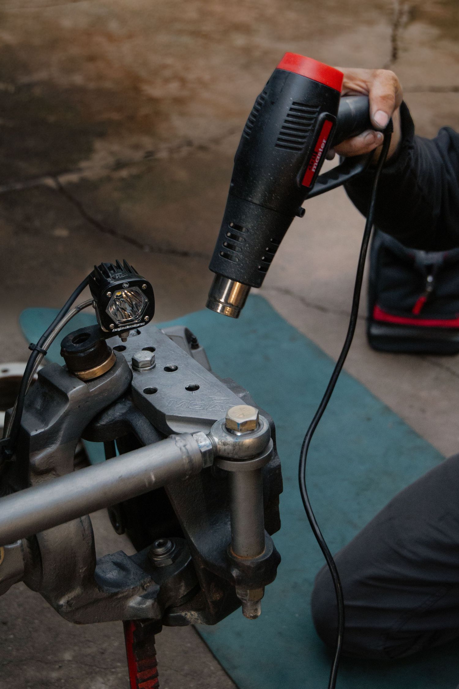 Close-up of mechanic using power tool on vehicle suspension component.