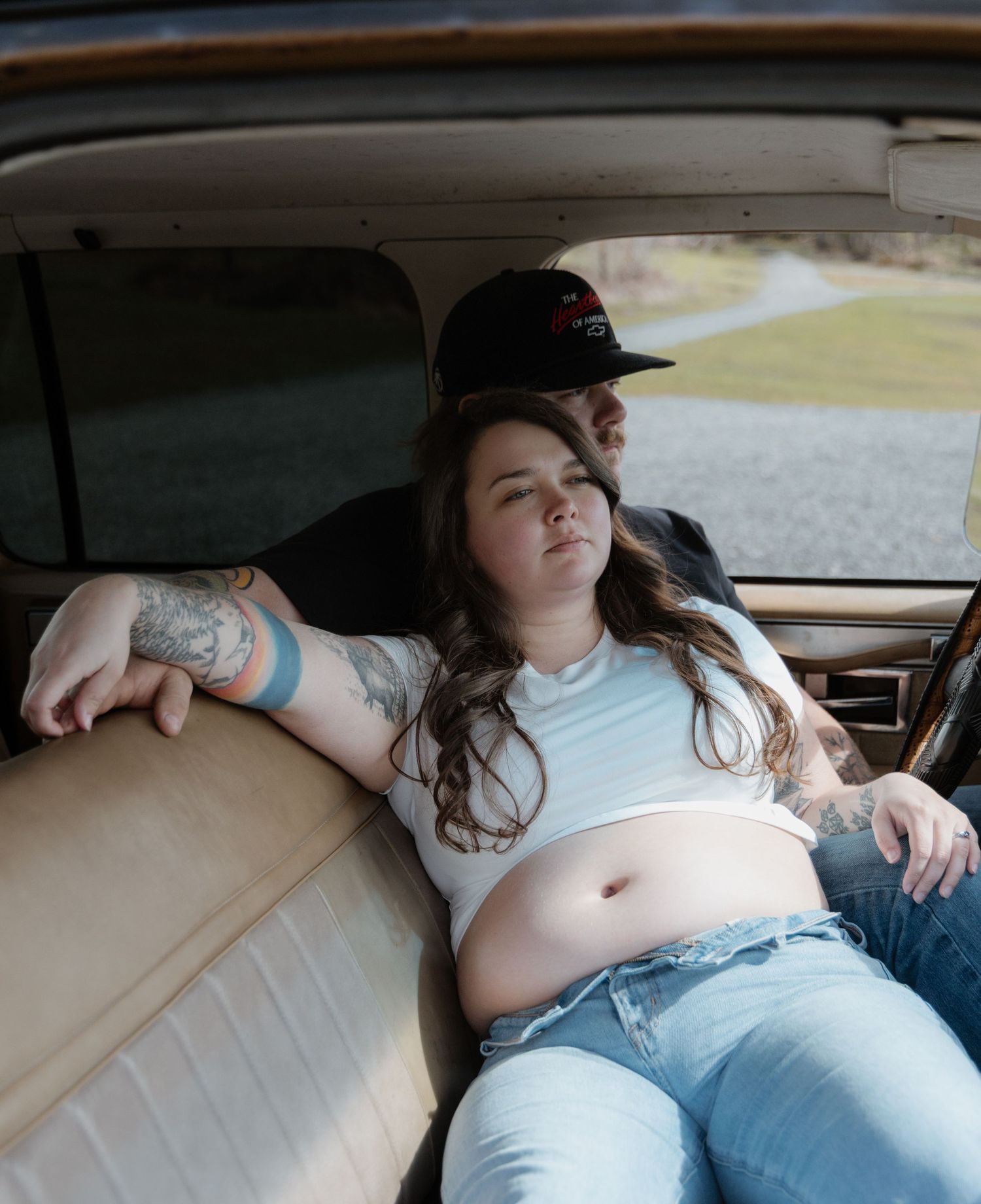 Person reclining in the backseat of a car wearing a white top and jeans while relaxing during a road trip.