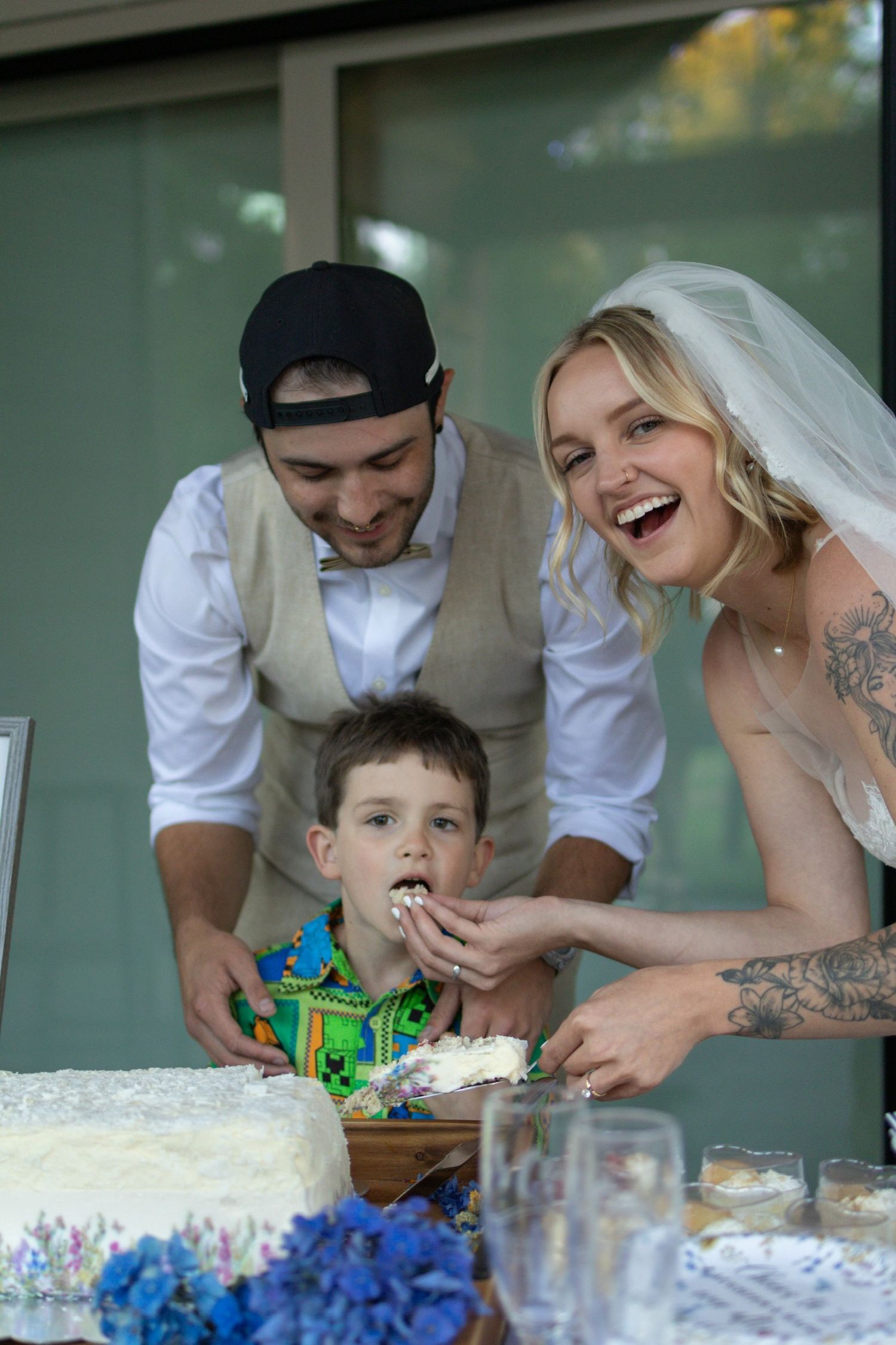 A playful moment at a wedding reception as the couple and a young child interact at the dessert table.