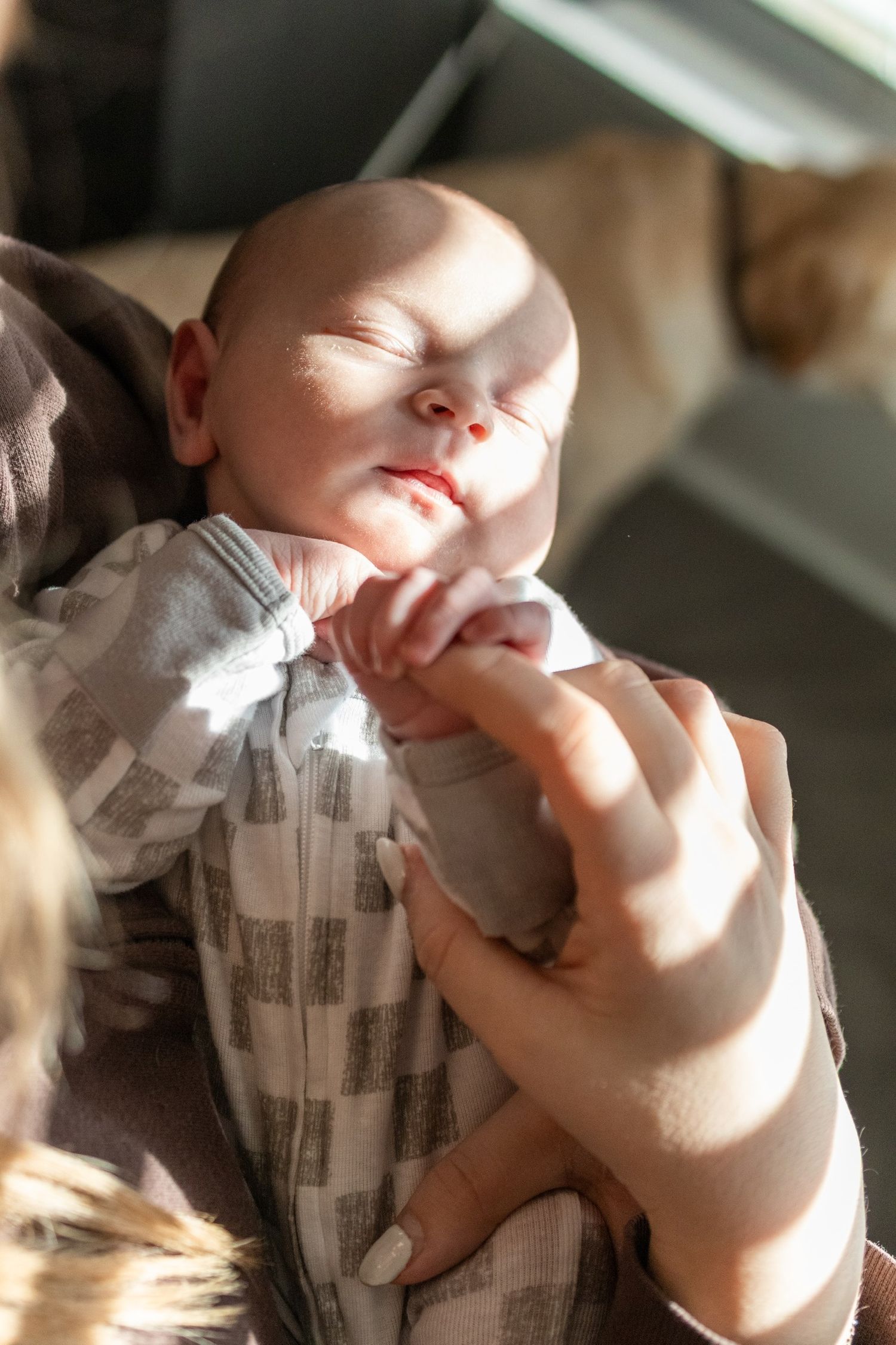 Sleeping infant bathed in warm sunlight wearing gray and white striped clothing.