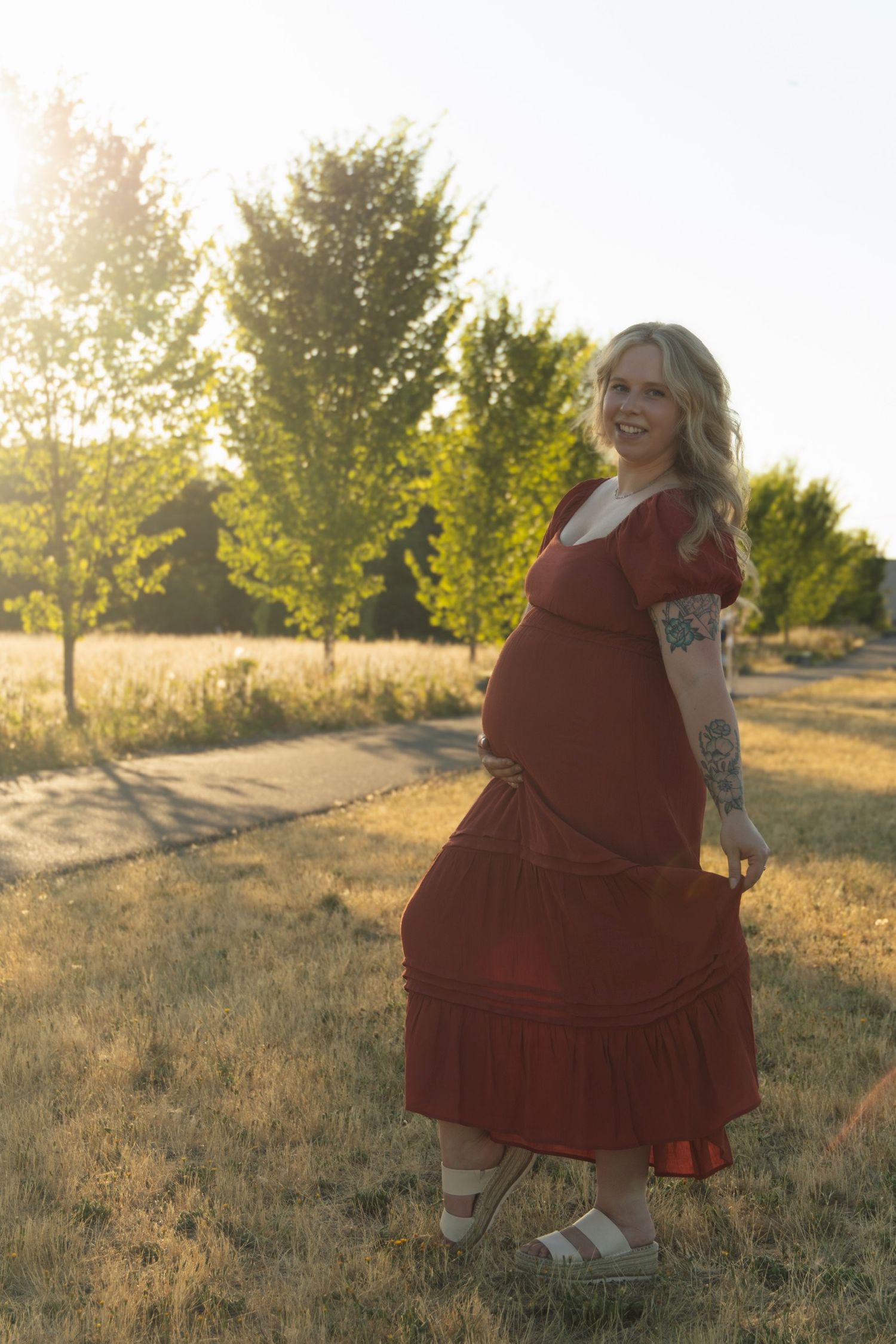 A person twirls in a red dress during sunset in a field.