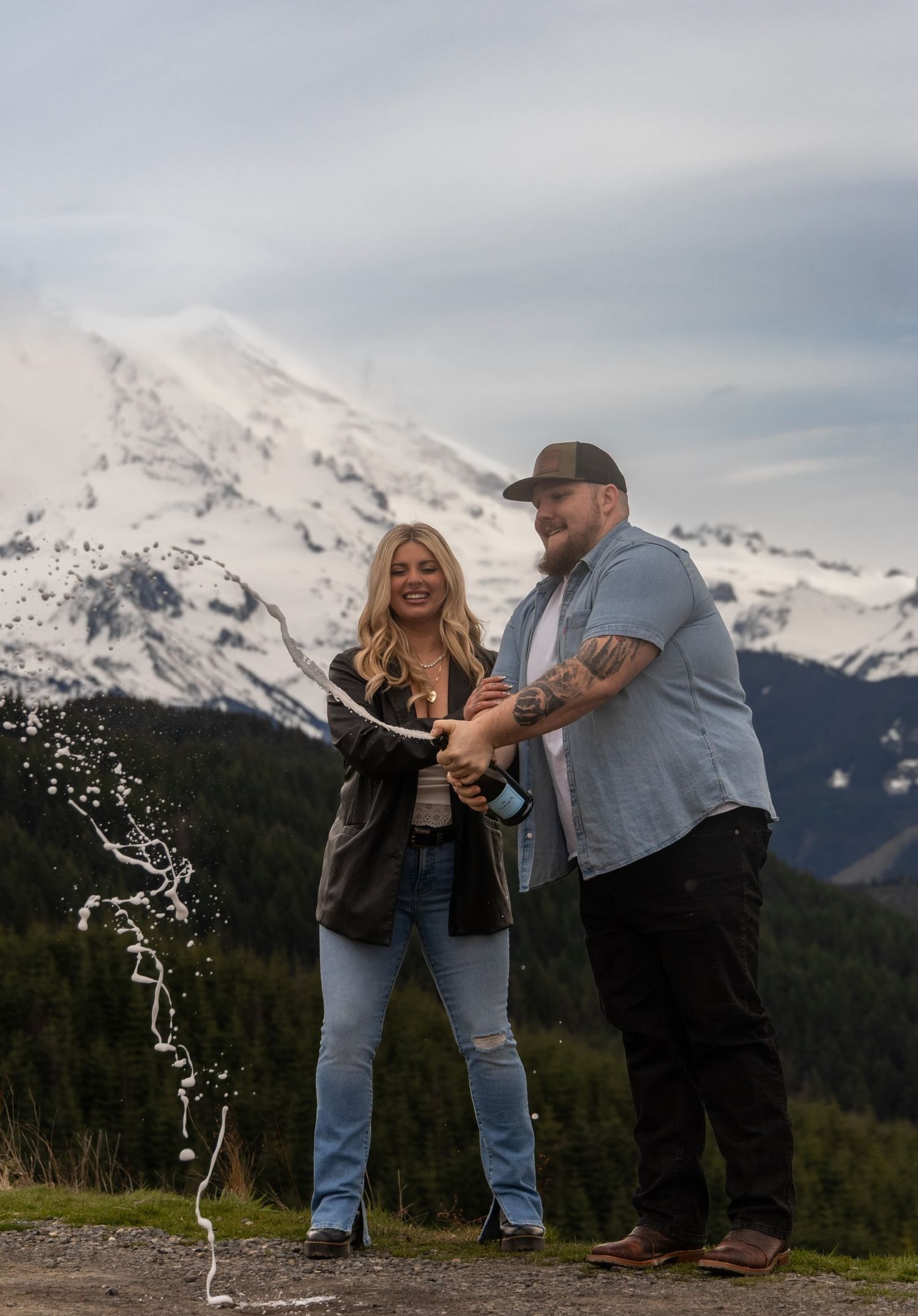Couple celebrating with champagne against a snowy mountain backdrop.