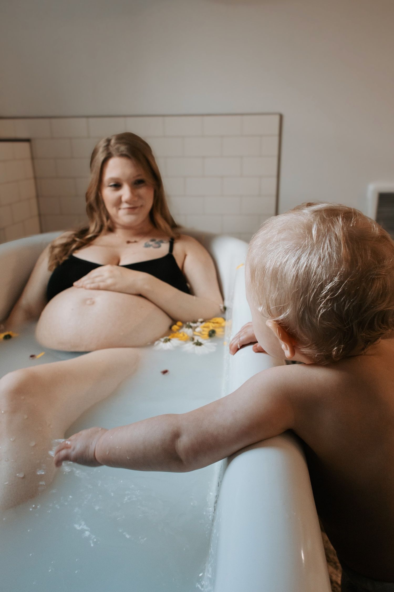 Artistic maternity milk bath photos with floating flowers.