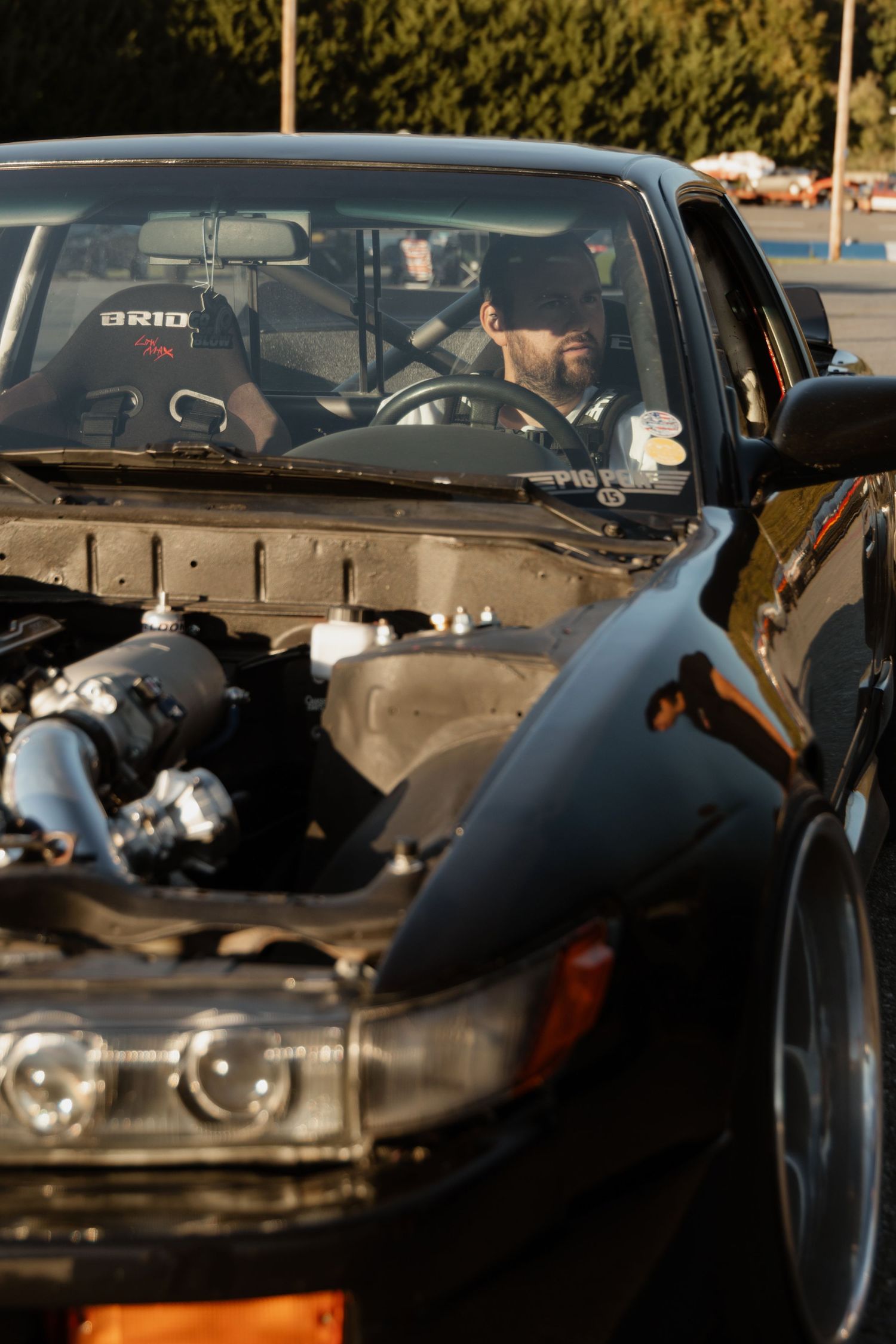Close-up view of black sports cars lined up at a car show, focusing on their sleek front-end designs and headlights.