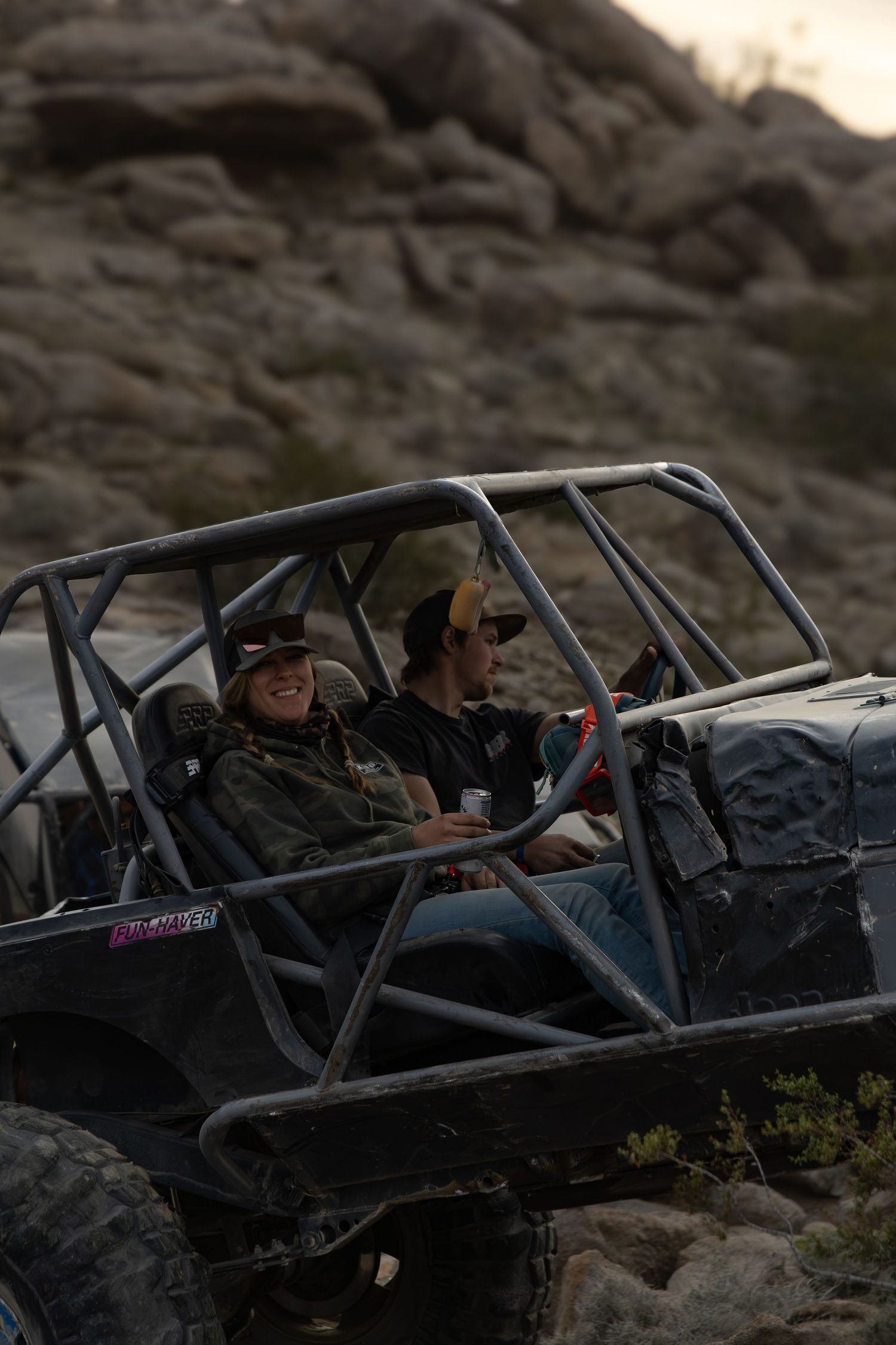 Black off-road buggy climbing rocky terrain at dusk.