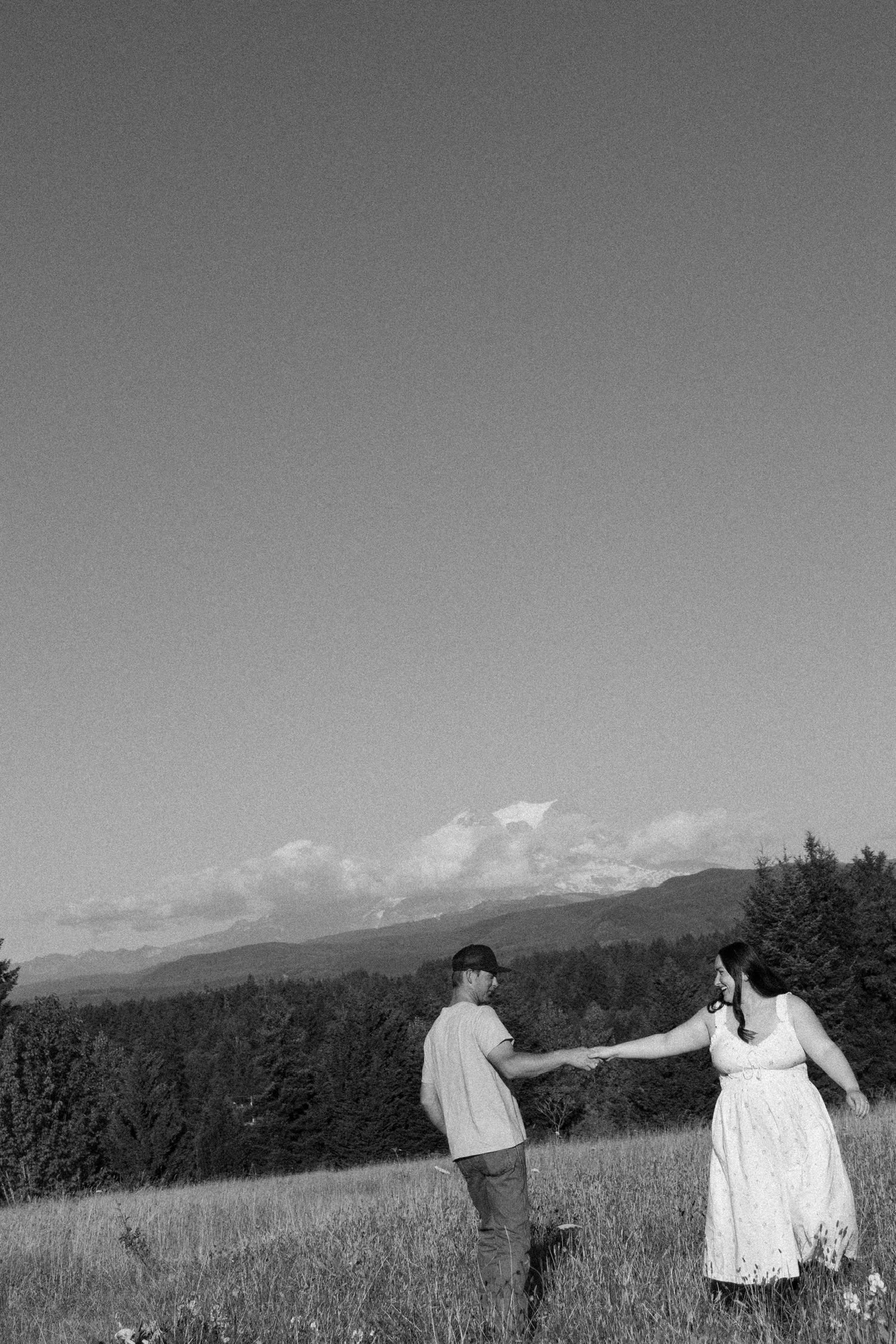 Black and white photo of a couple dancing in a mountain meadow.