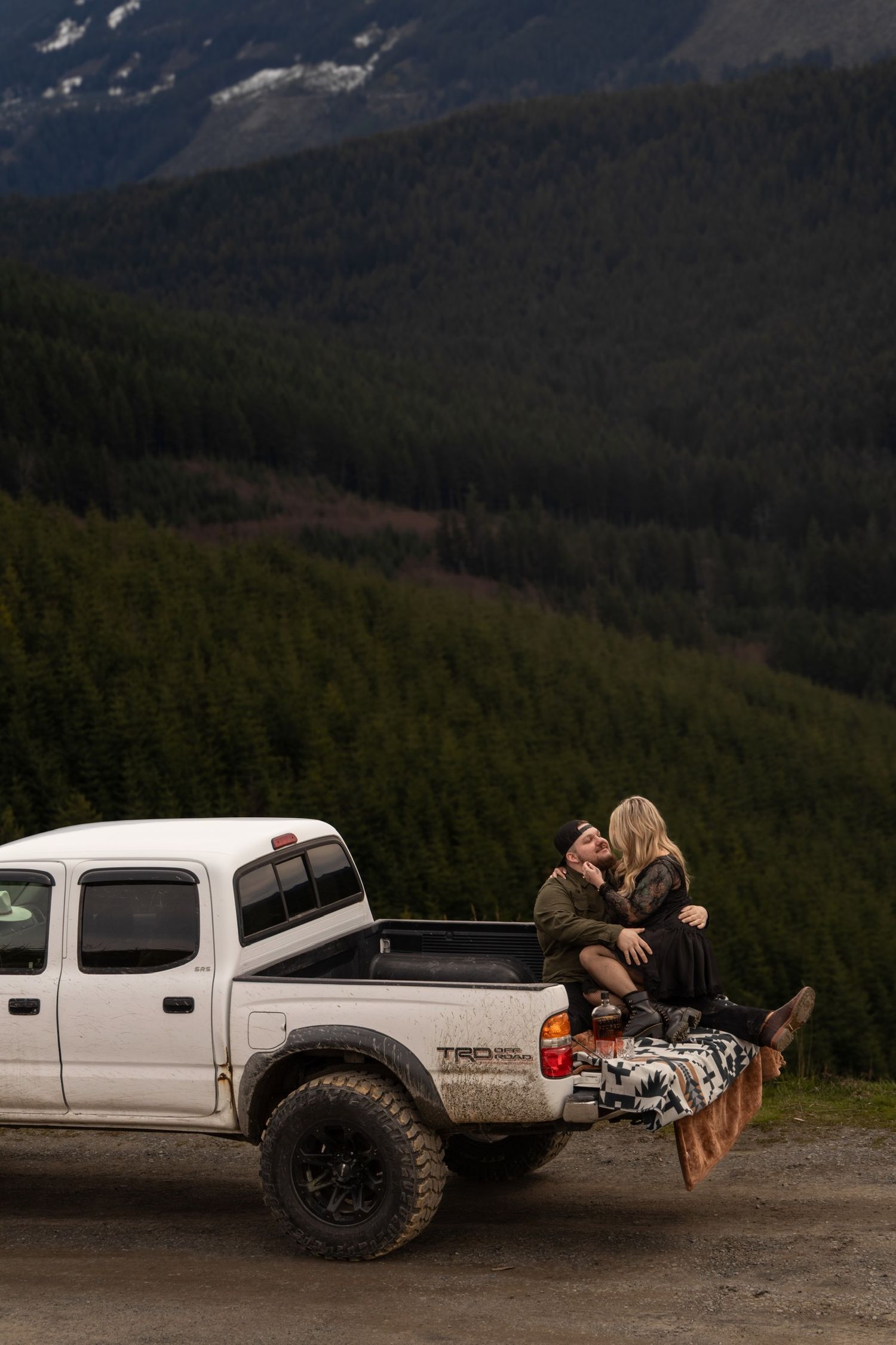White pickup truck parked on mountain overlook with forest backdrop.