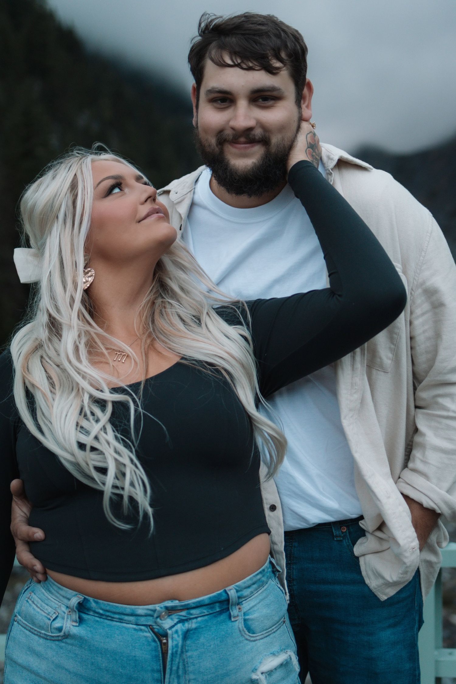 Couple in casual attire sharing playful moments against a moody backdrop.
