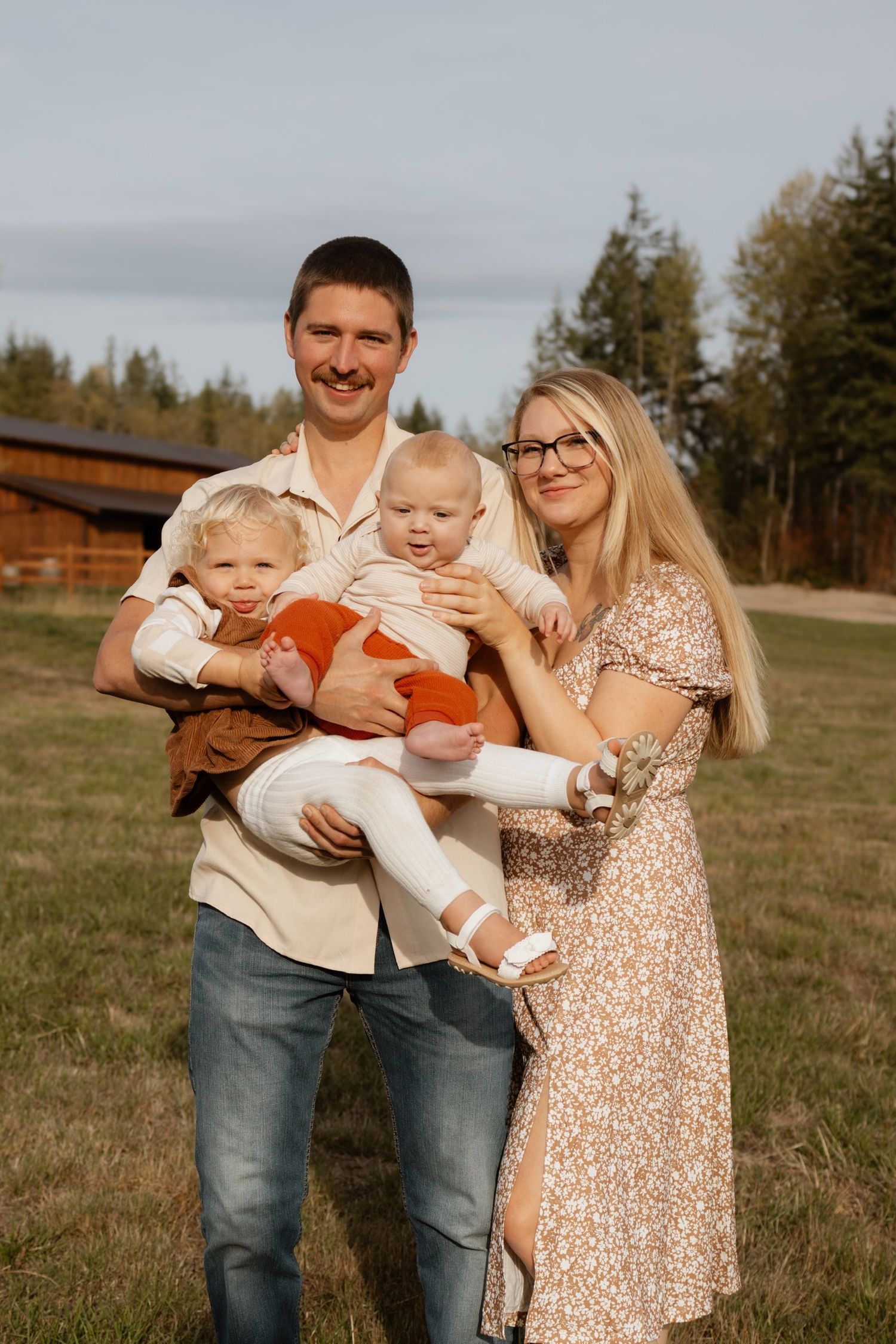Family portrait outdoors in front of a rustic wooden building.