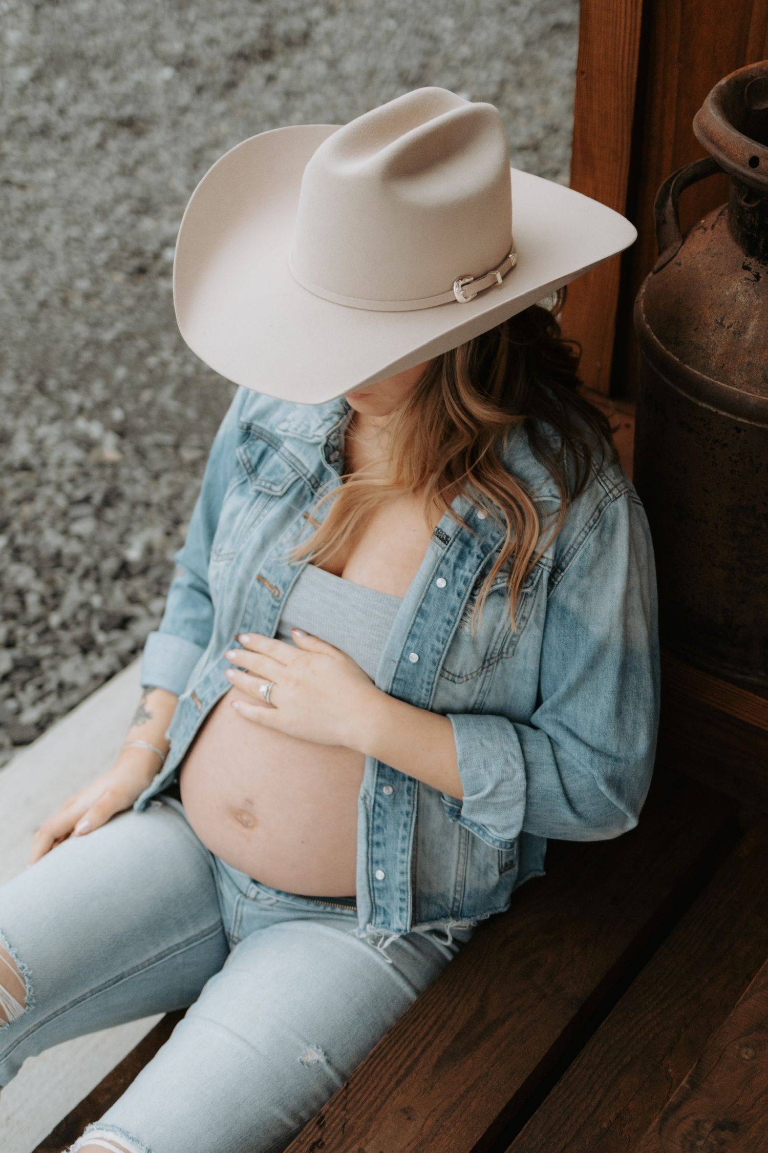 Maternity photo featuring woman in cowboy hat and denim on wooden steps.