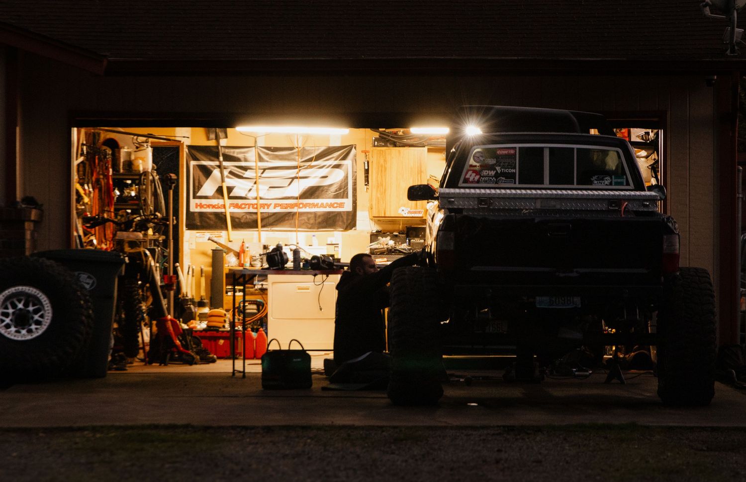 Dimly lit auto repair garage interior with vehicles and equipment visible.