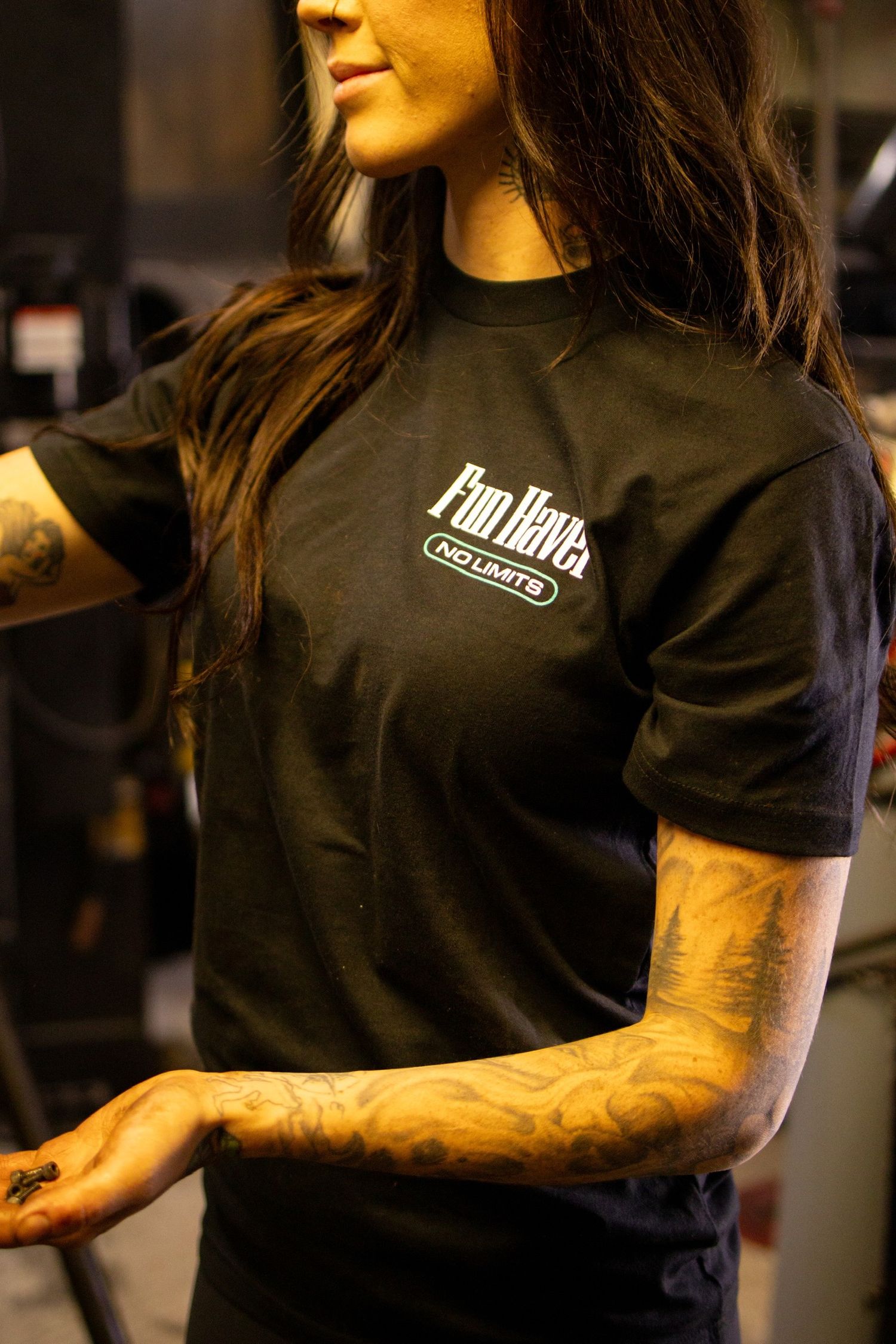 Collection of black t-shirts with branded logos displayed on dark background.