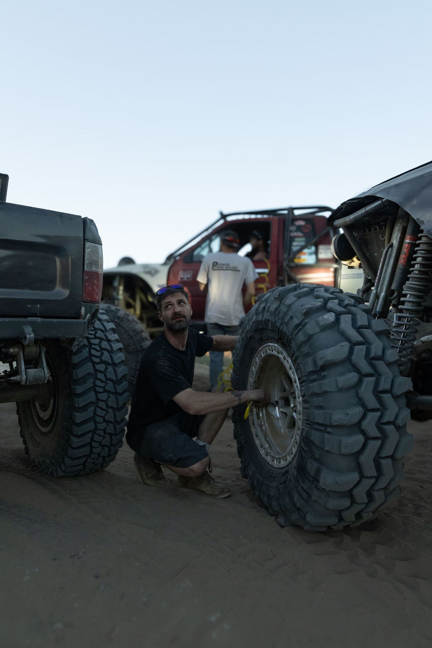 A series of off-road truck tires being mounted and installed on vehicles in a garage setting.