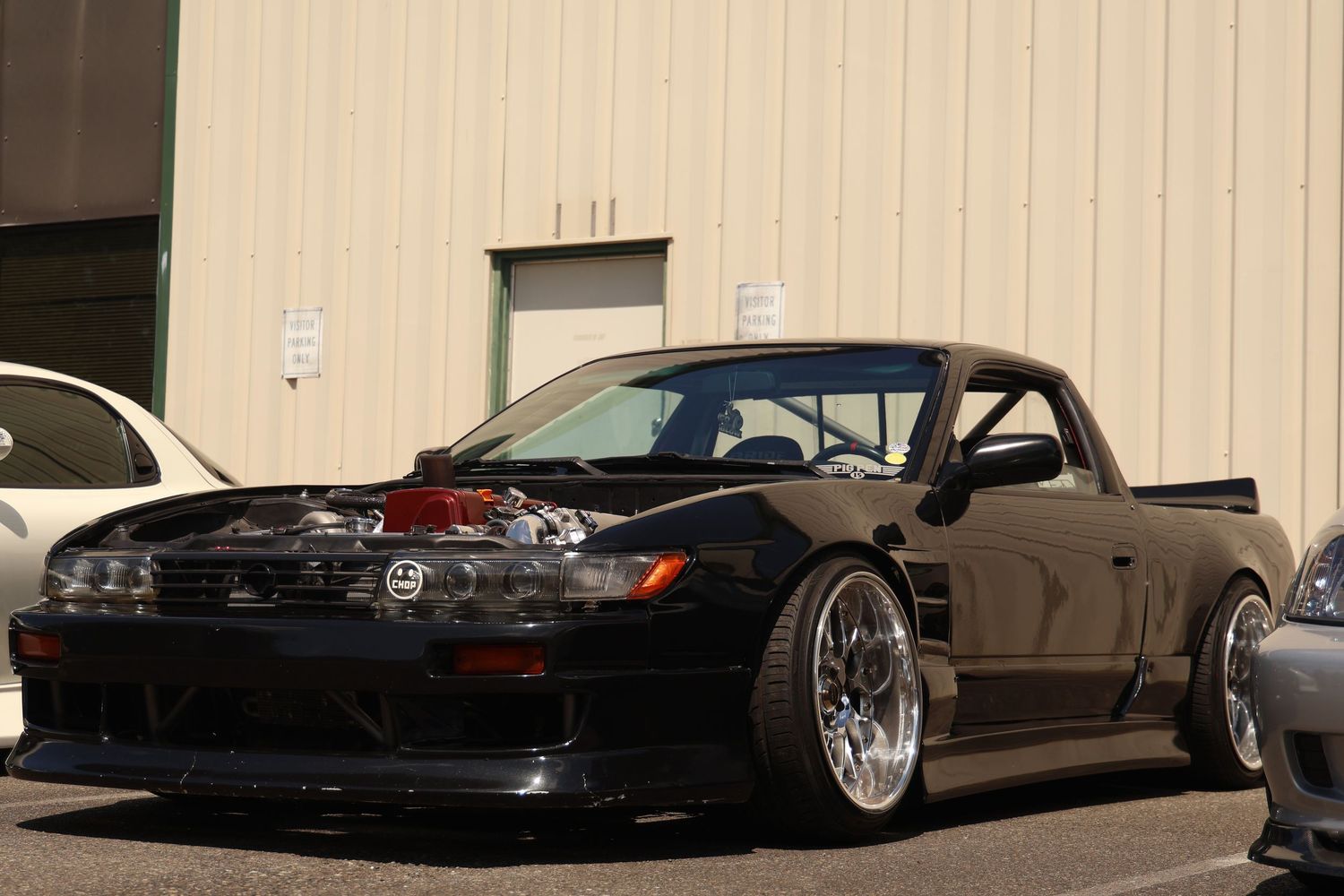 A row of black lowered cars parked side by side showcasing custom modifications and sleek styling.