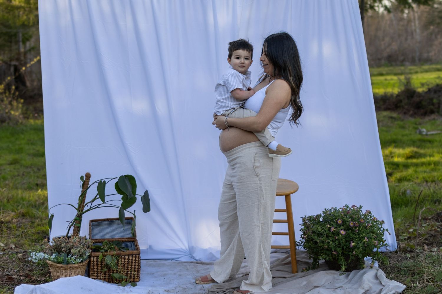 Couple poses in front of white backdrop outdoors during photo session.