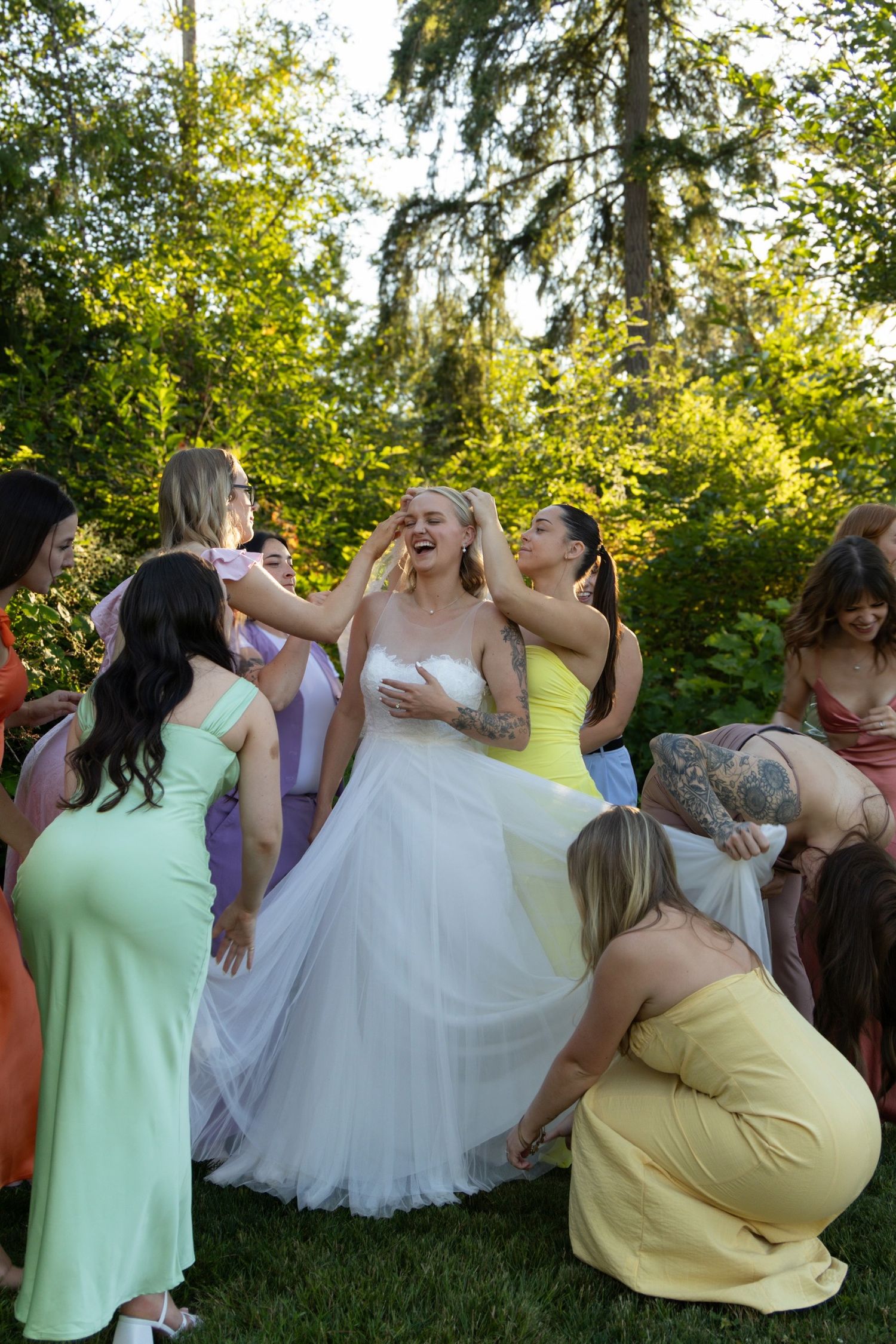 Wedding party in colorful dresses laughing and dancing together outdoors.