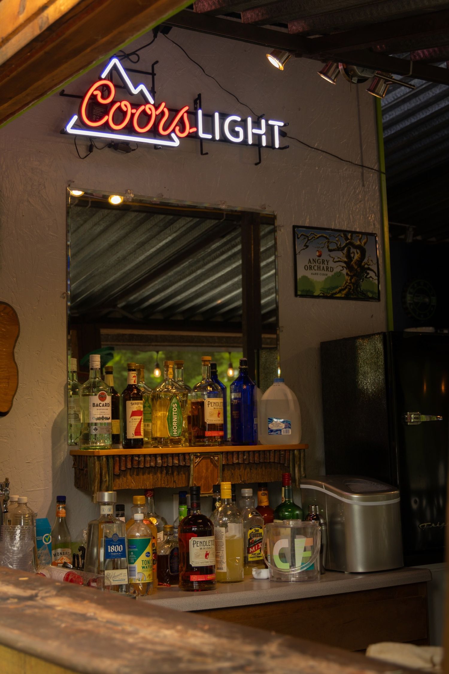A dimly lit bar with neon Coors Light signs and bottles displayed on shelves.