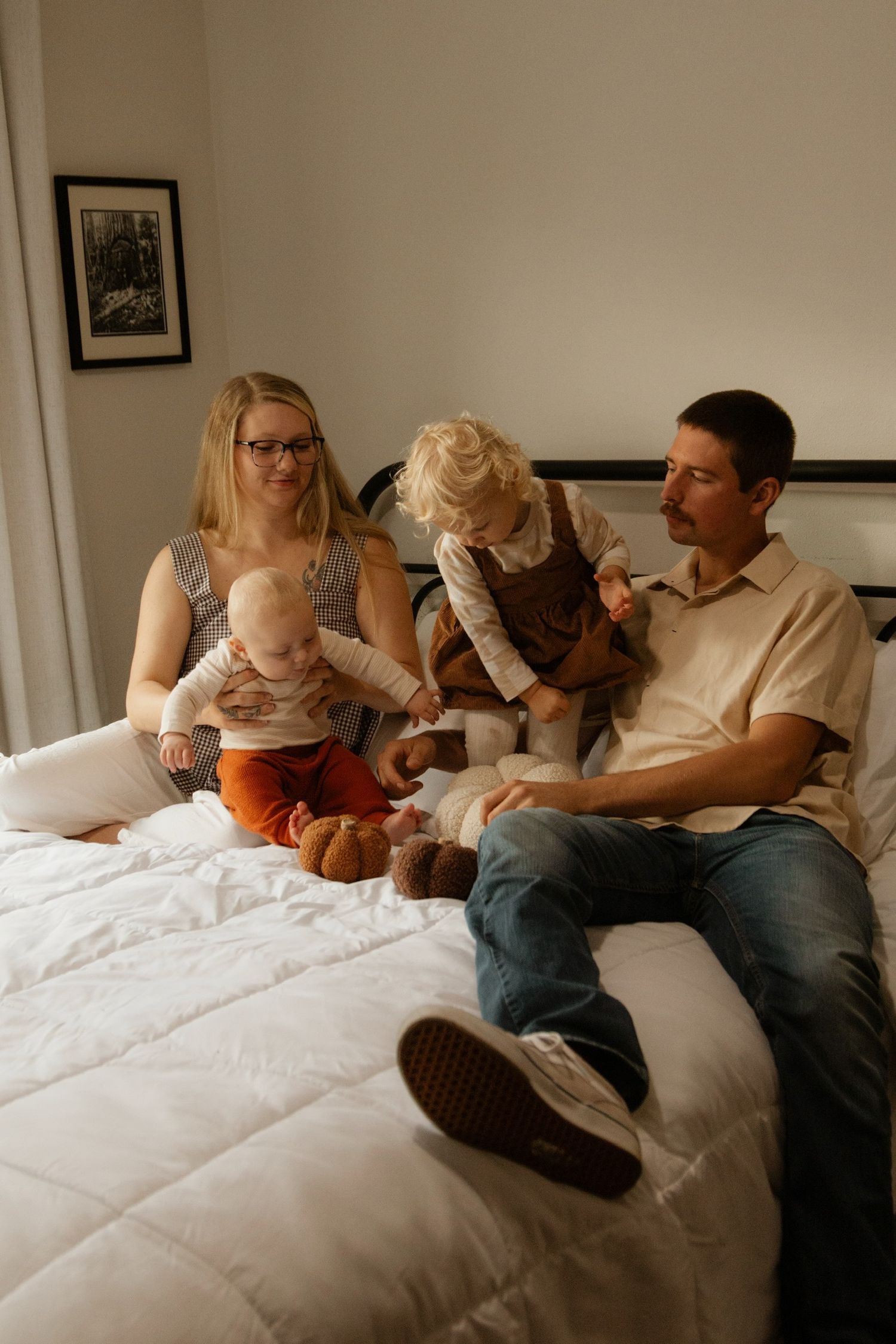 Candid family moments captured on white bedding during indoor lifestyle photography session.