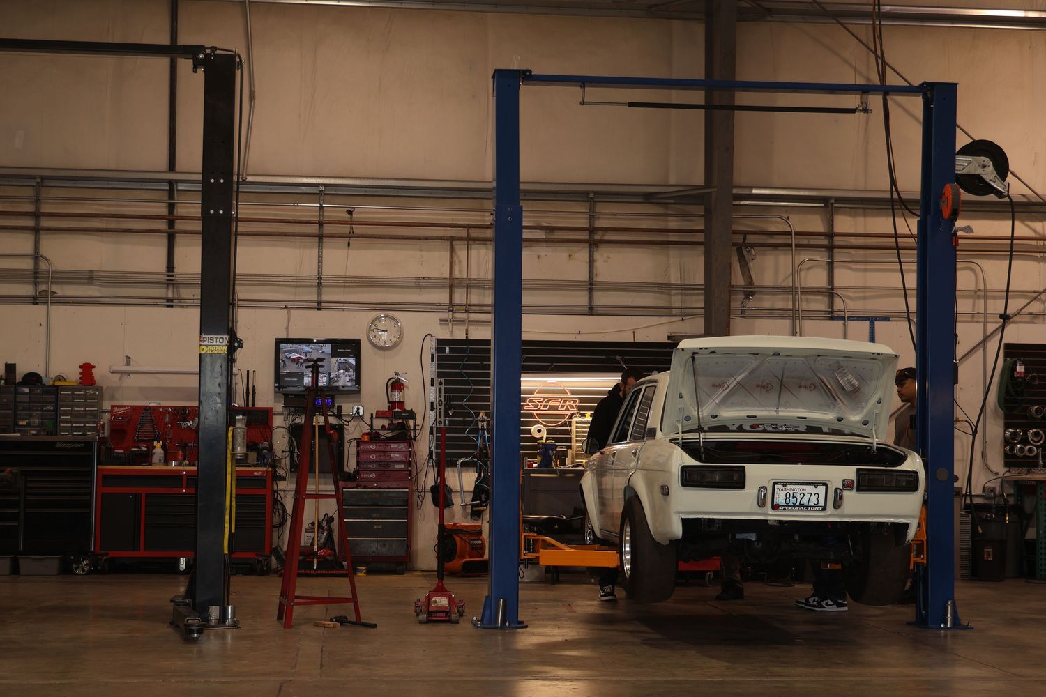 Large industrial warehouse interior with blue support columns and various equipment and vehicles visible.