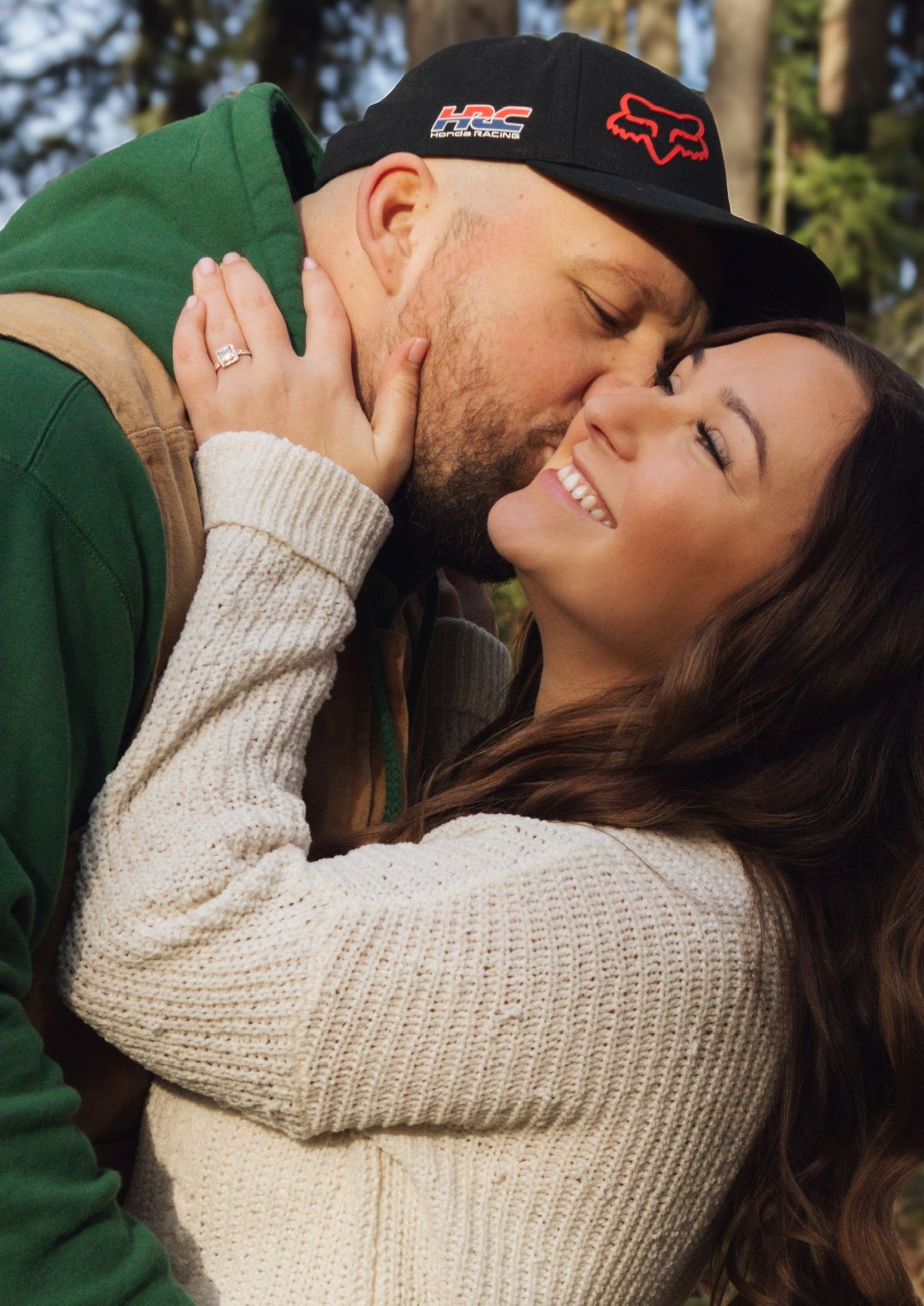 Intimate moment between couple wearing casual outdoor clothing in a forest setting.