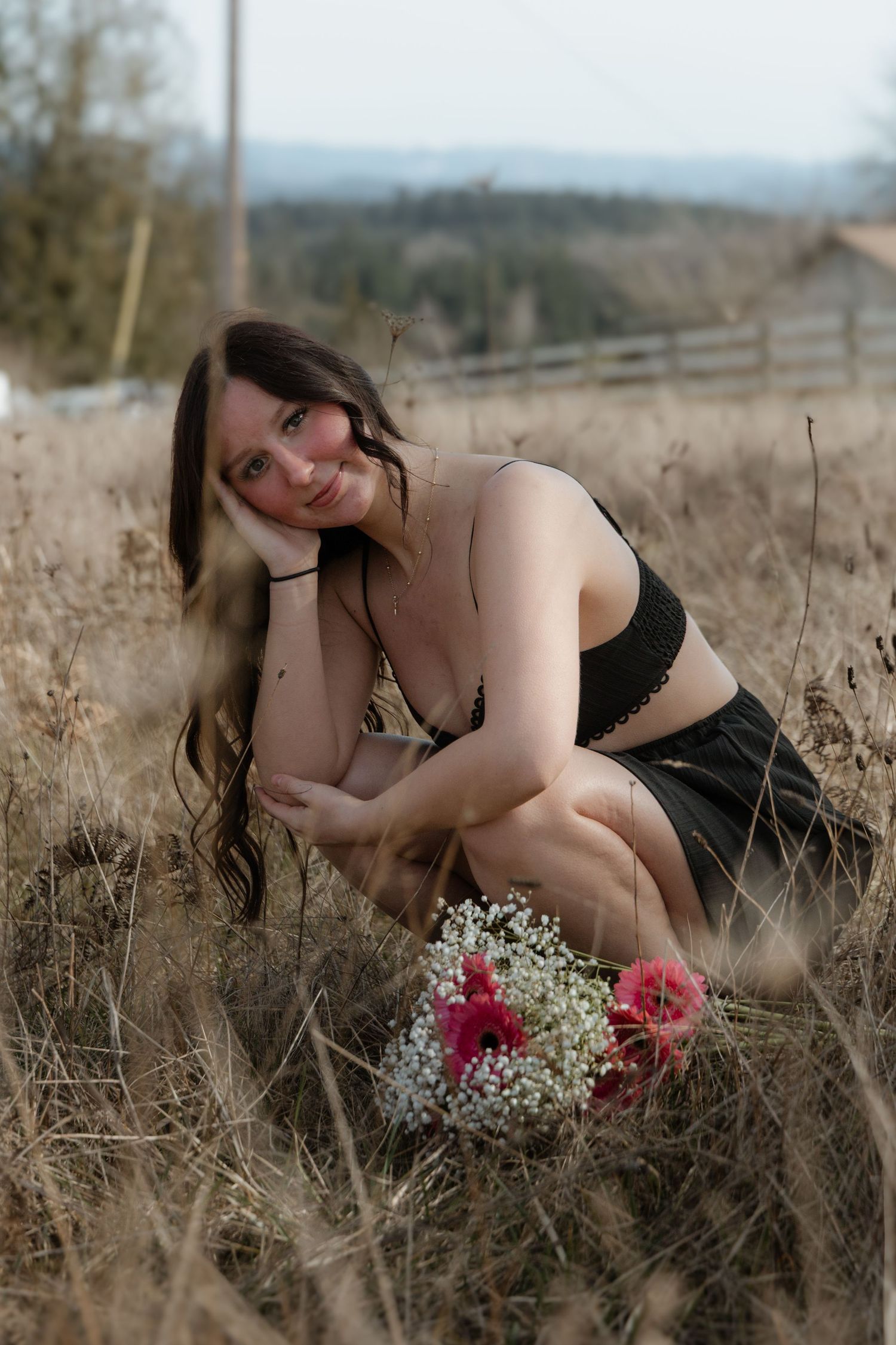 Artistic boudoir photoshoot in a golden field with dried grasses and delicate flowers at sunset.