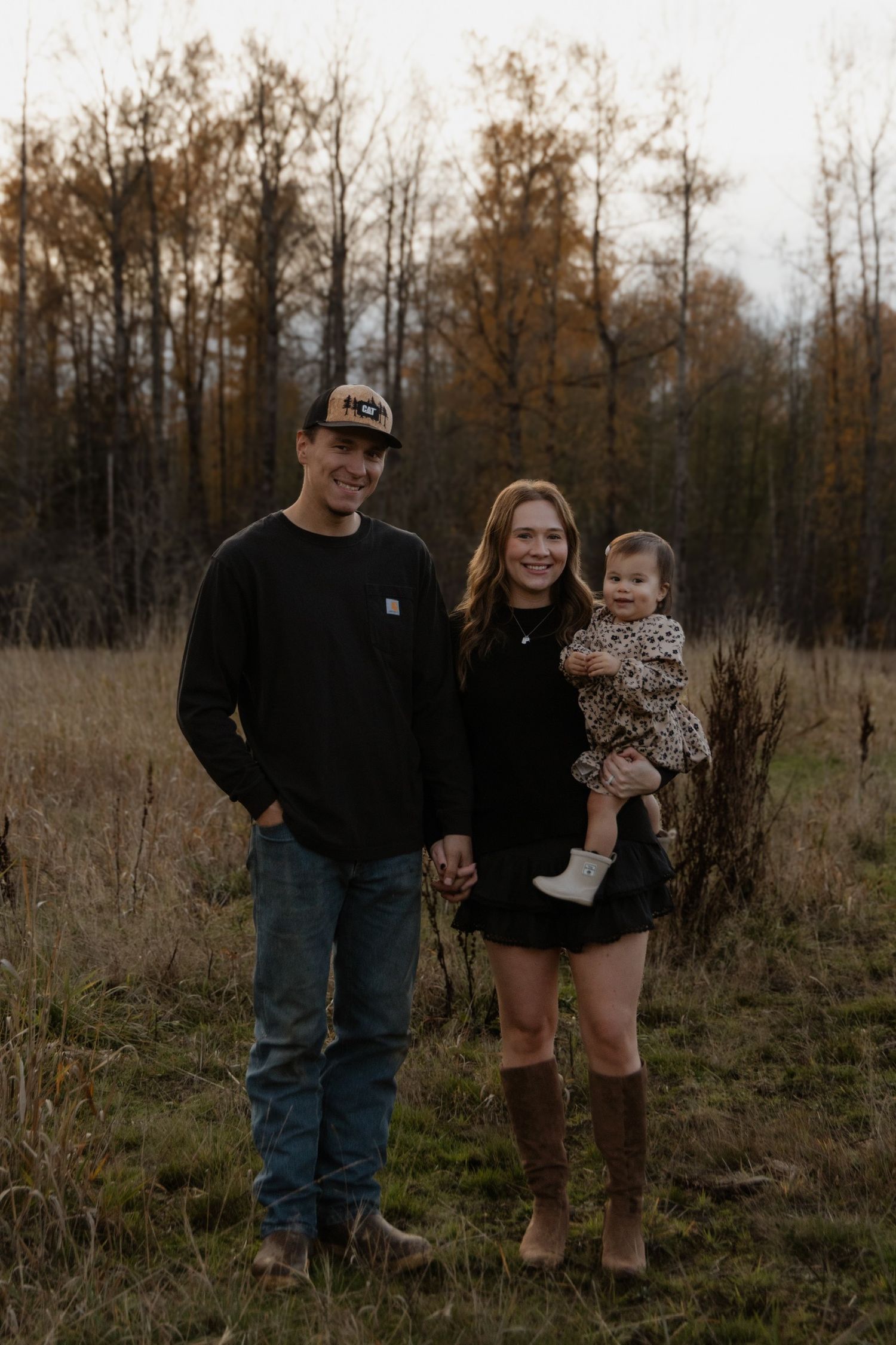 Family portrait session in rustic field during autumn evening.