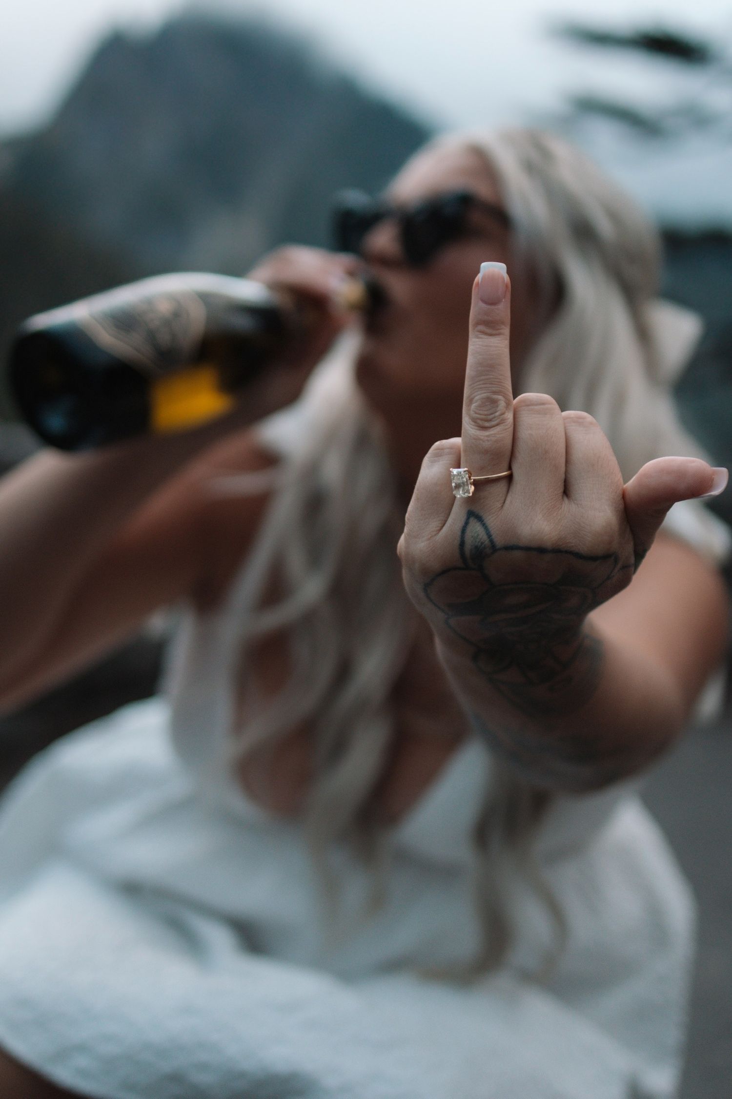 A defiant gesture photographed against a moody mountain landscape.