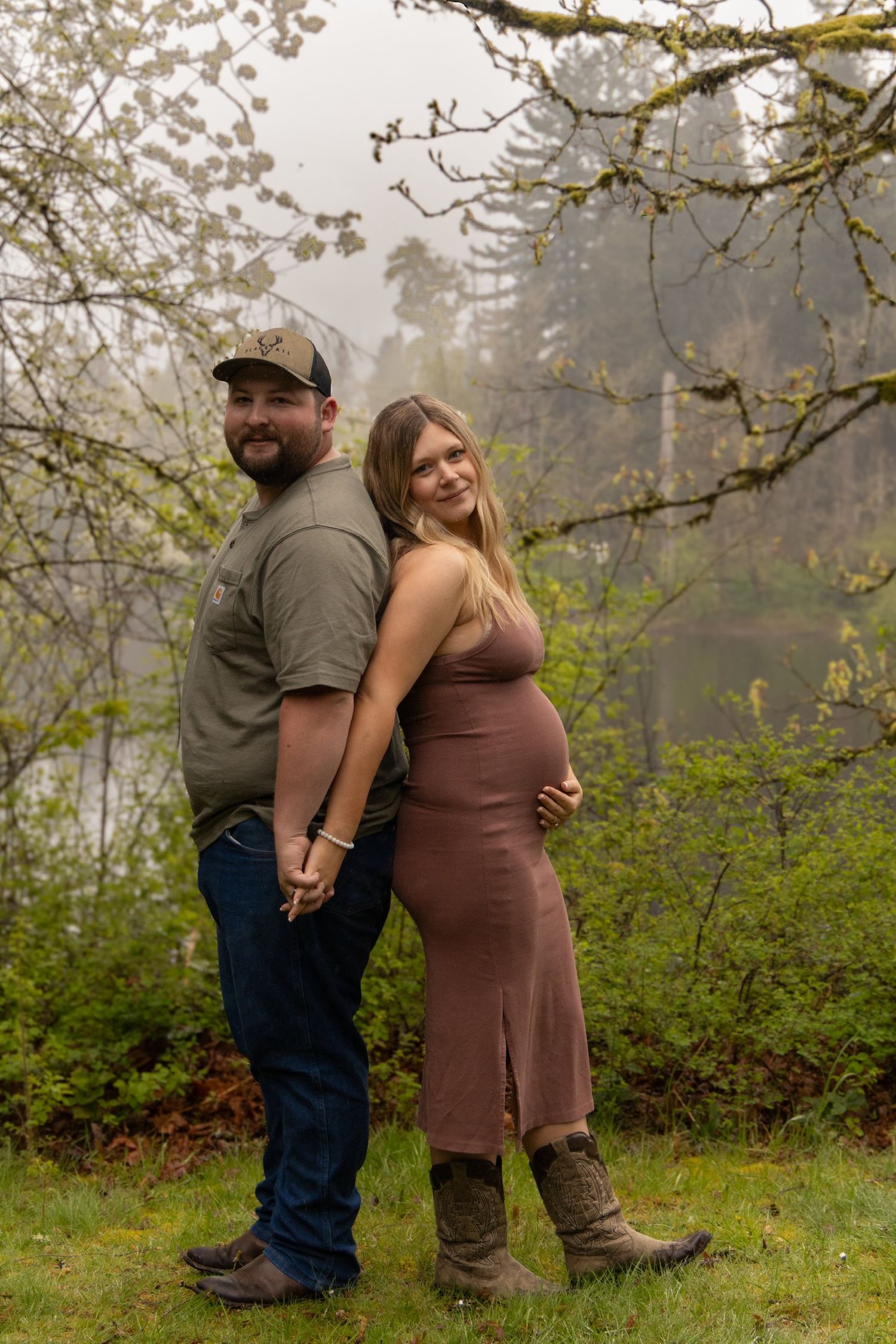 Romantic maternity photos of couple in misty forest setting.