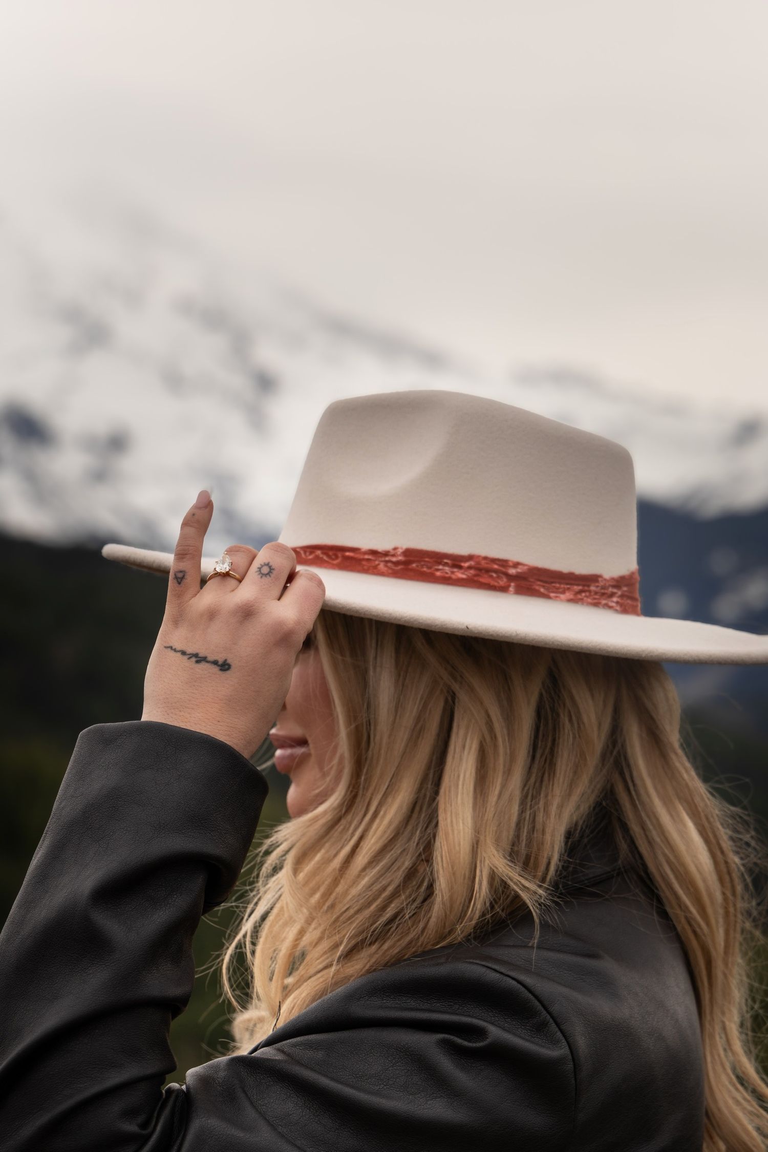Person wearing a white cowboy hat against a mountainous backdrop.