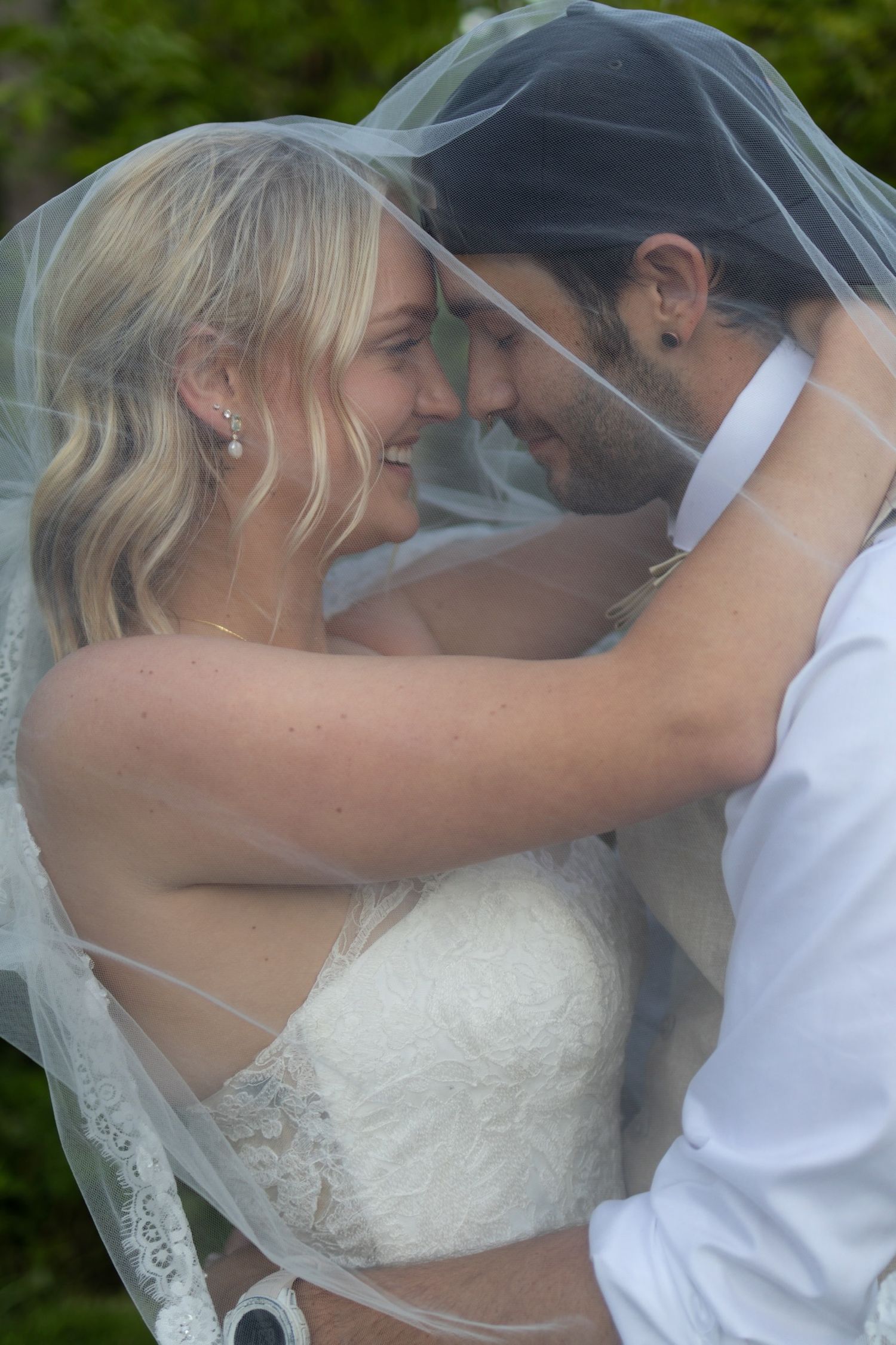 Romantic wedding moment captured through a delicate veil in an outdoor setting.