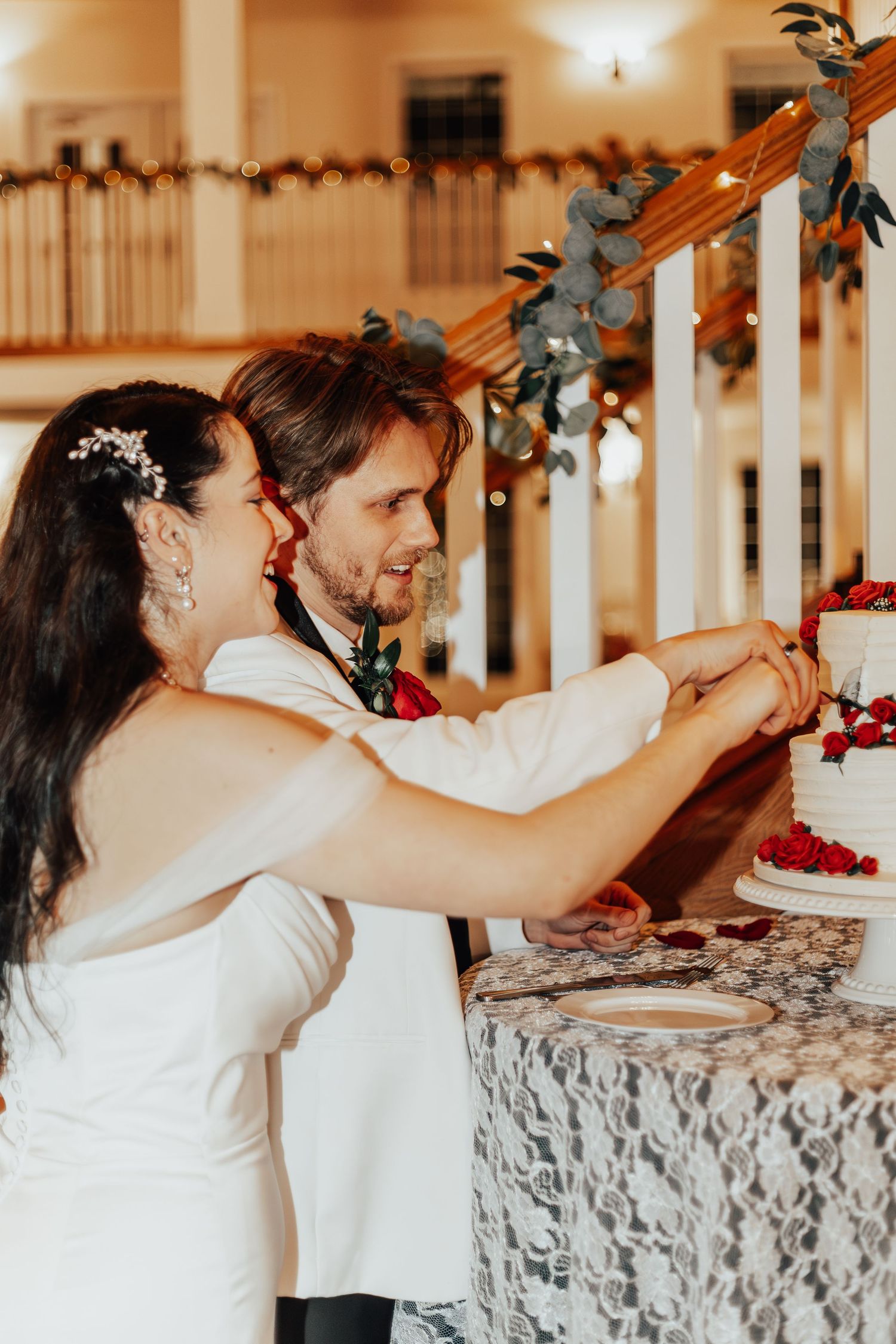Playful cake cutting sequence at an indoor wedding reception with decorative lighting.