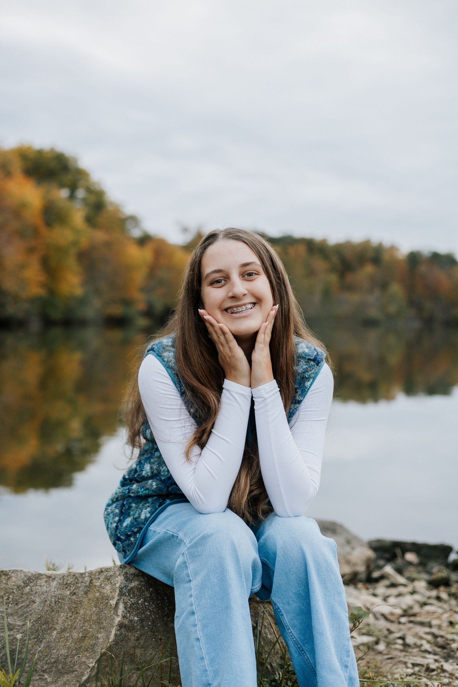 Playful poses by lakeside with autumn landscape and reflective water in background.