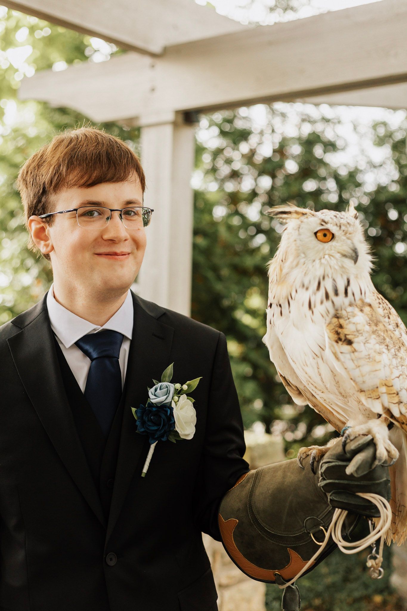 A majestic owl perched with a handler during an outdoor wedding ceremony.