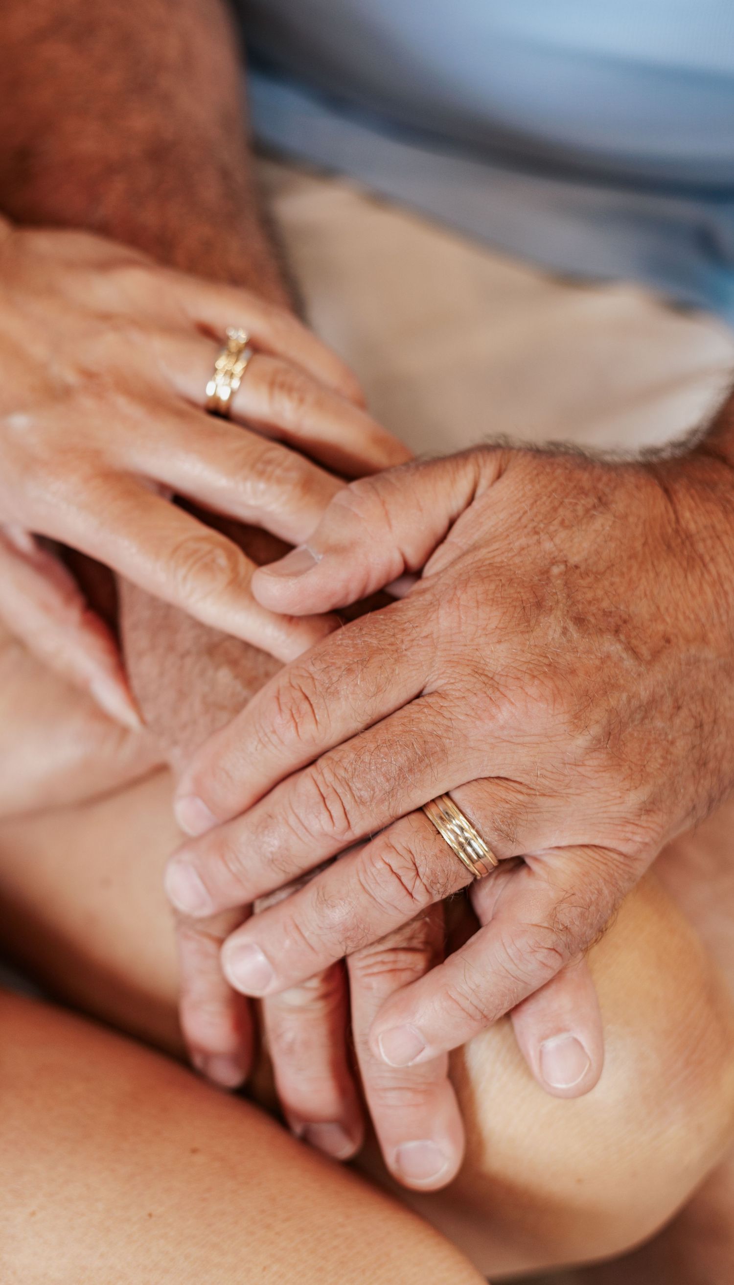 Close-up of hands wearing wedding rings resting together.