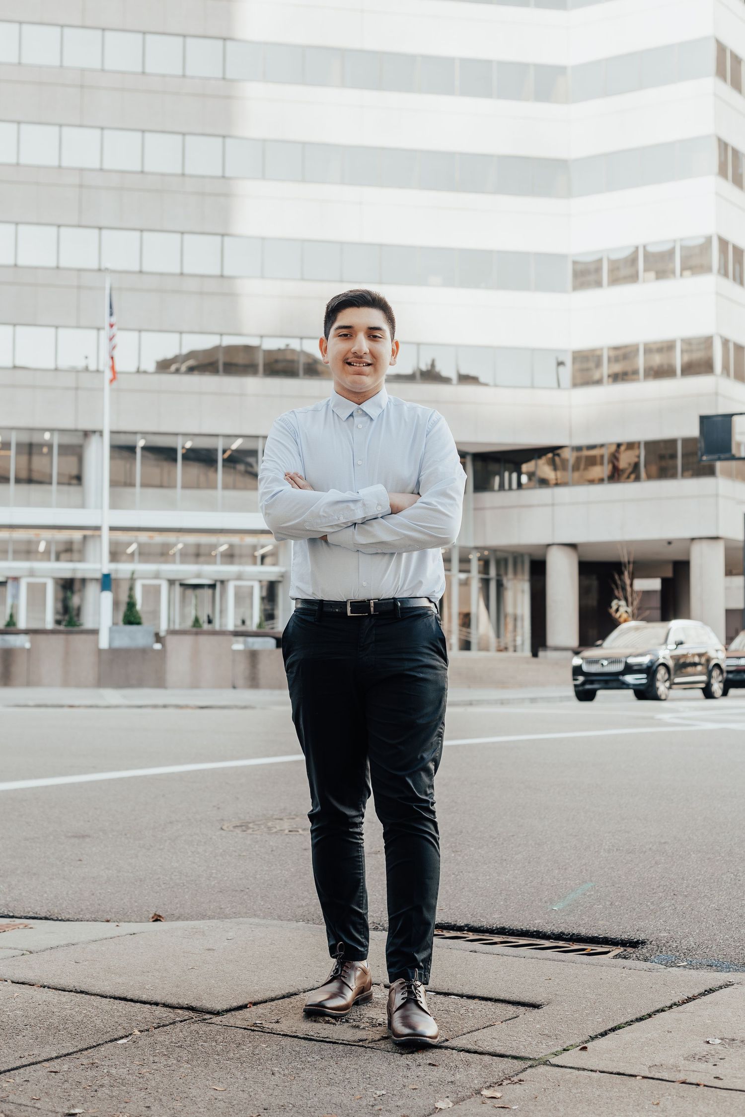 Person in business attire poses confidently on concrete plaza near modern office buildings.
