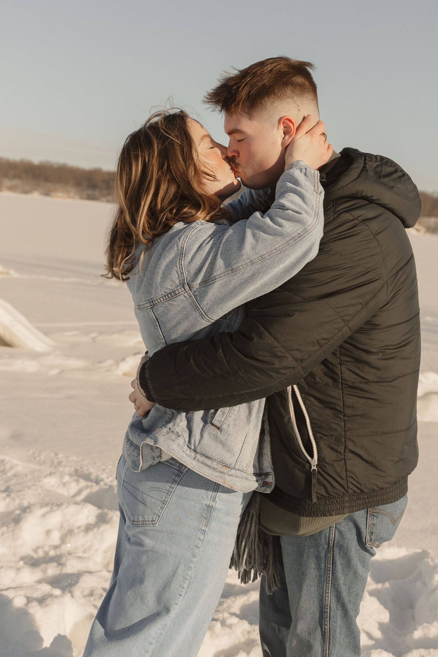 A romantic winter embrace captured against a snowy landscape.