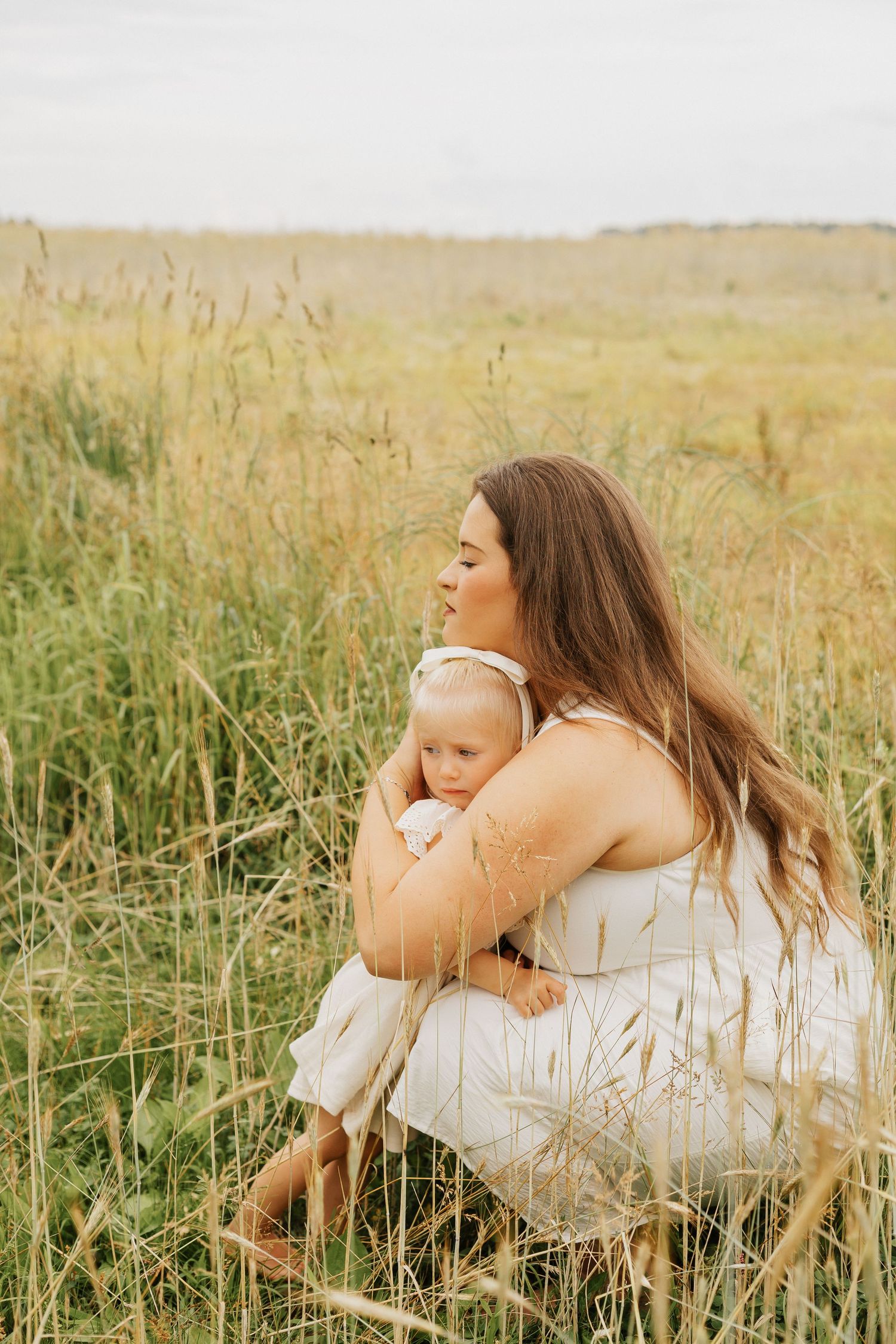 Family resting together in a golden wheat field during sunset.