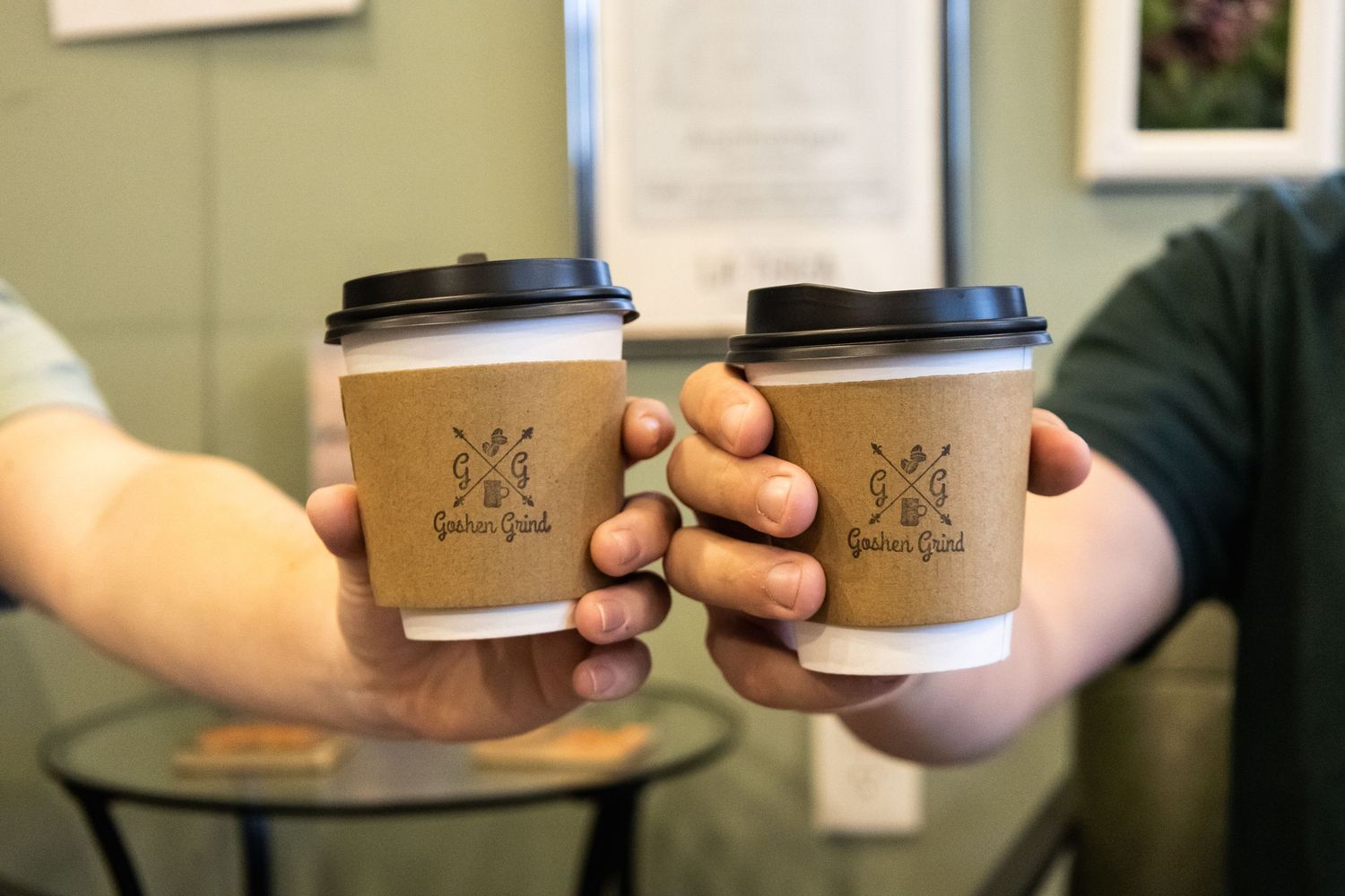 Coffee cups being passed between hands at local coffee shop counter.
