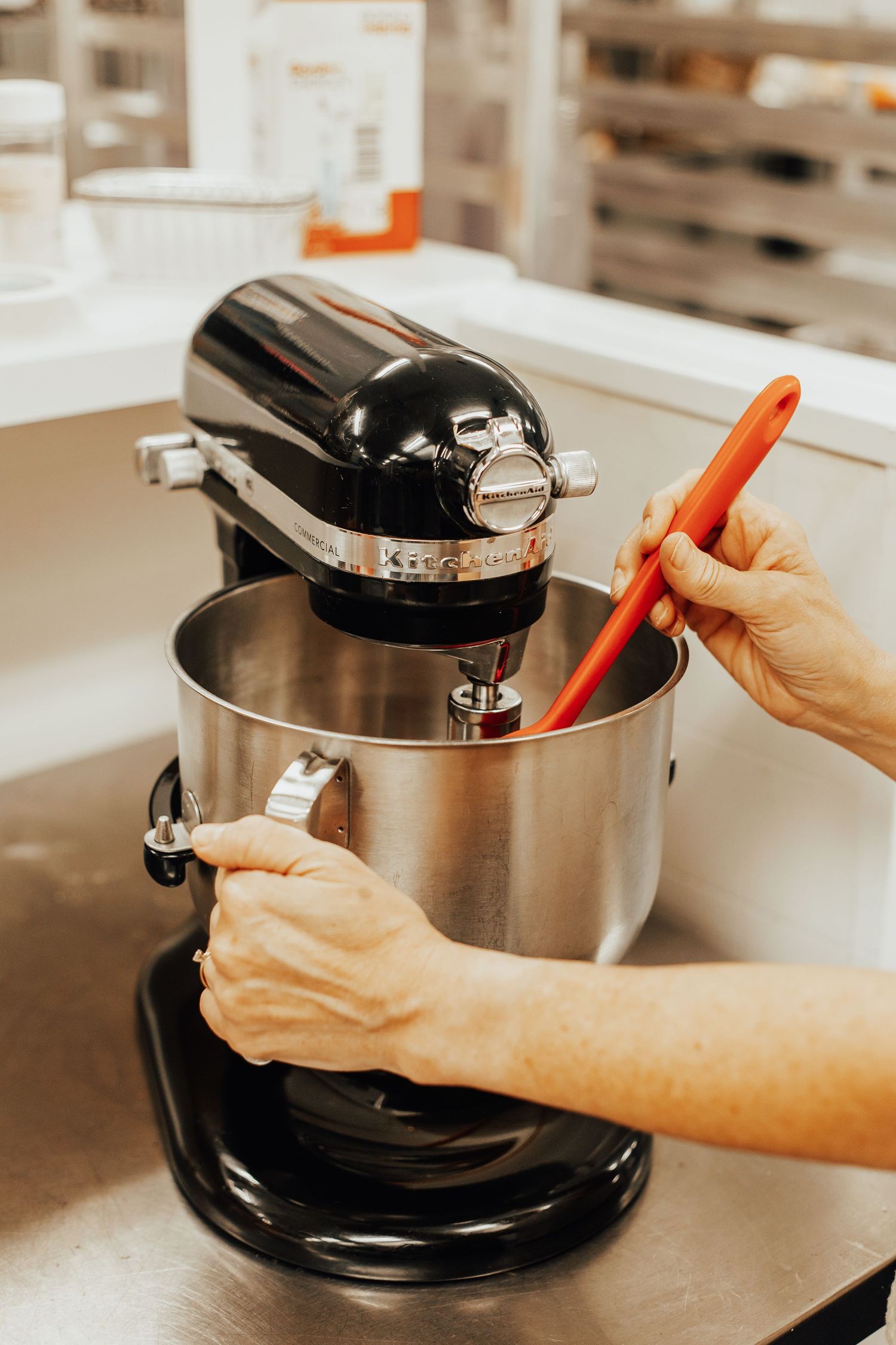 Hands adjusting settings on a stainless steel commercial kitchen appliance.