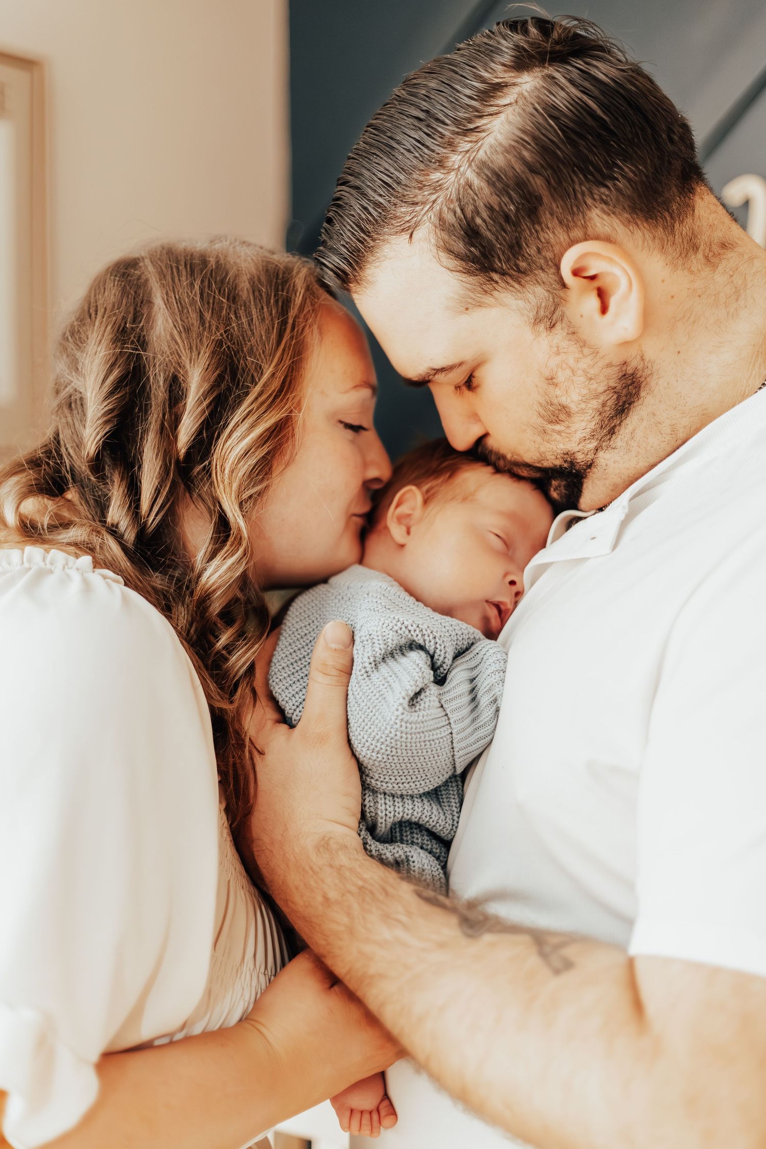 Intimate family moment with newborn baby being embraced by parents.